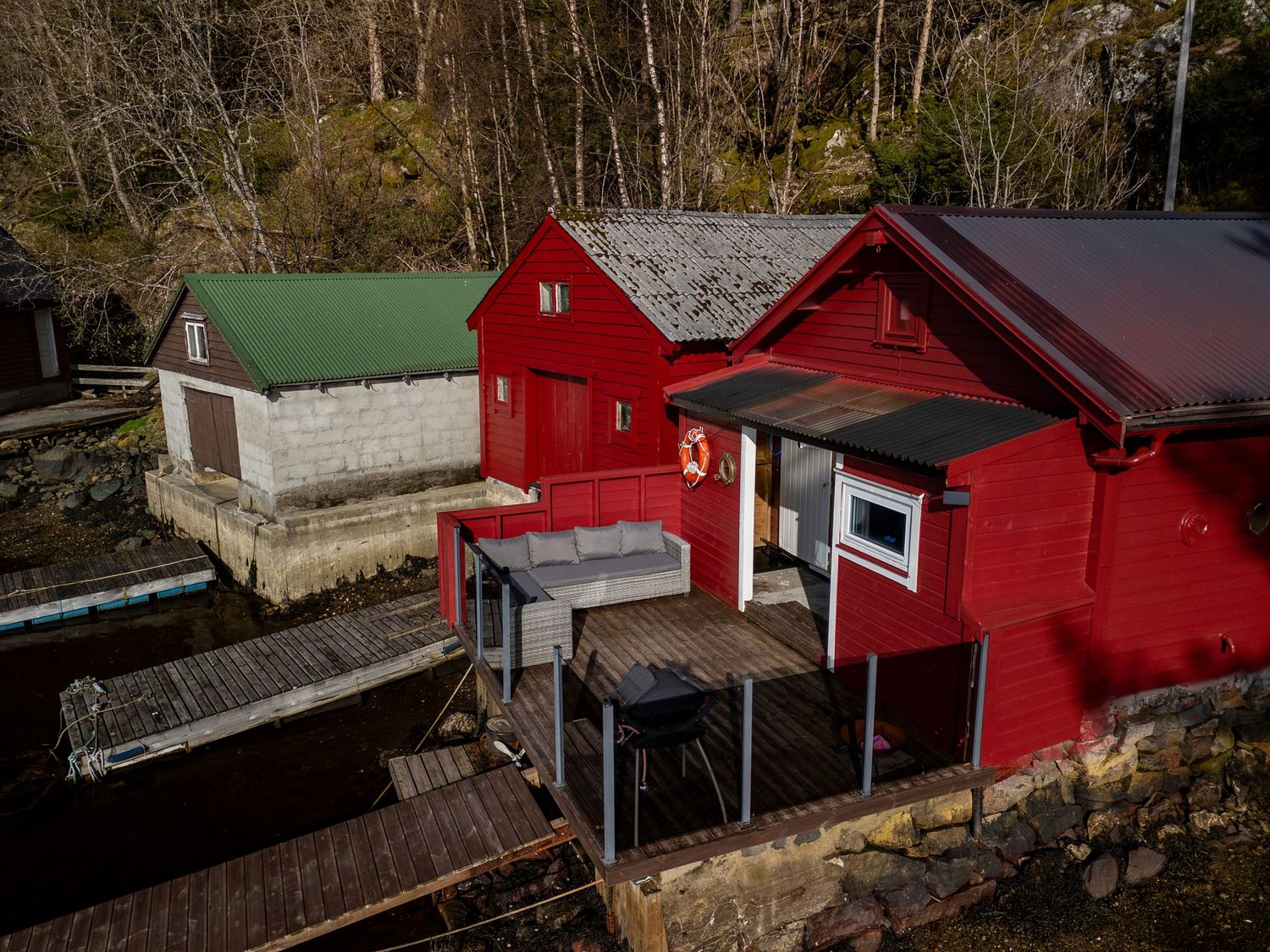 Red and green waterfront boat sheds with raised platforms and docks extending over the water.