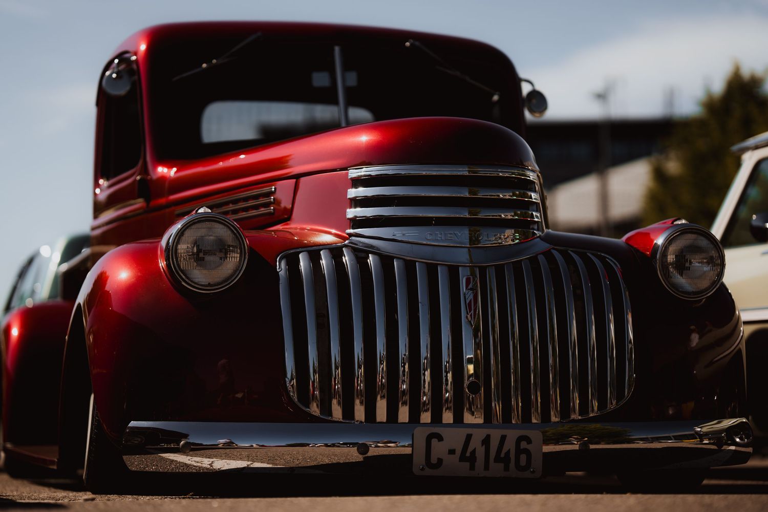 Classic red Chevrolet pickup truck front end with chrome grille at sunset.