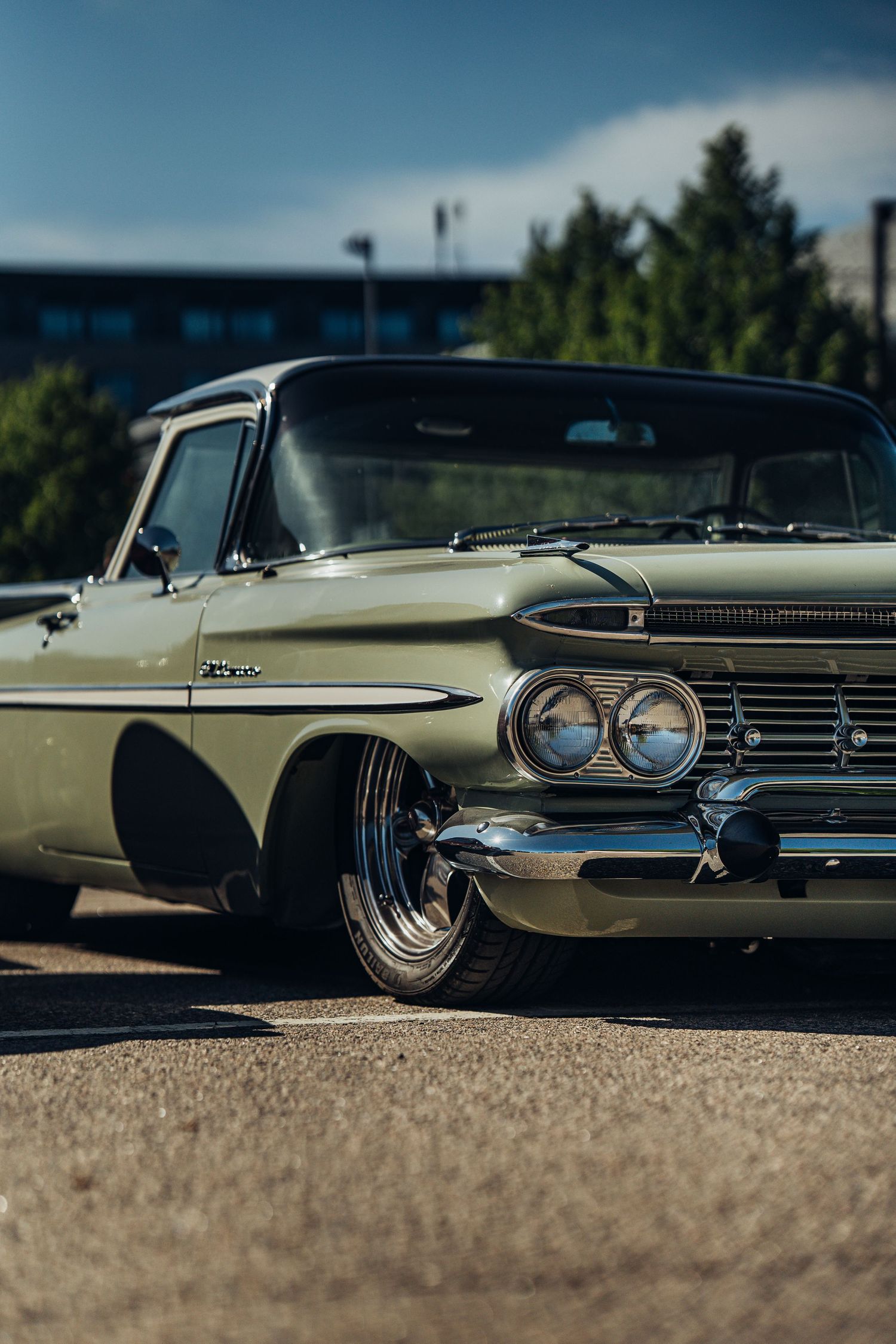 Classic beige Chevrolet Impala photographed from a low angle showing its distinctive chrome grille and headlights.