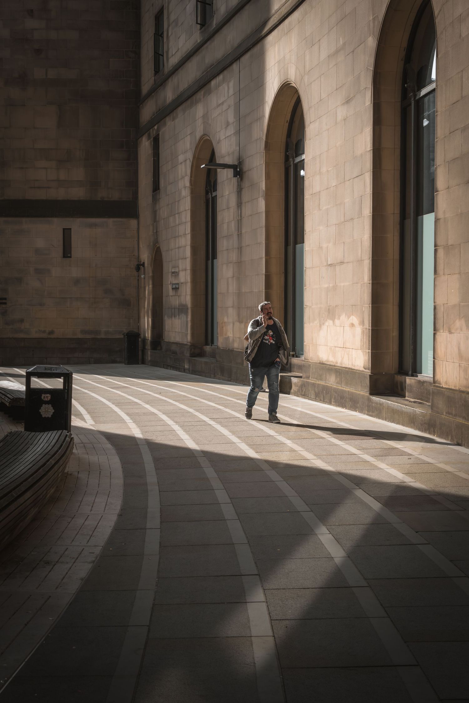 Curved architectural walkway with dramatic shadows and lighting in a stone building interior.