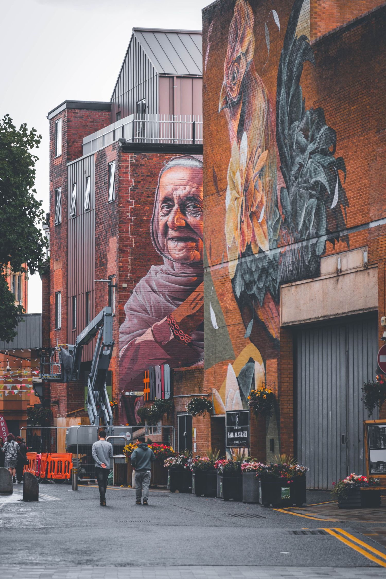 Large-scale urban mural art on brick building wall showing vibrant colors and artistic expression in an industrial setting.