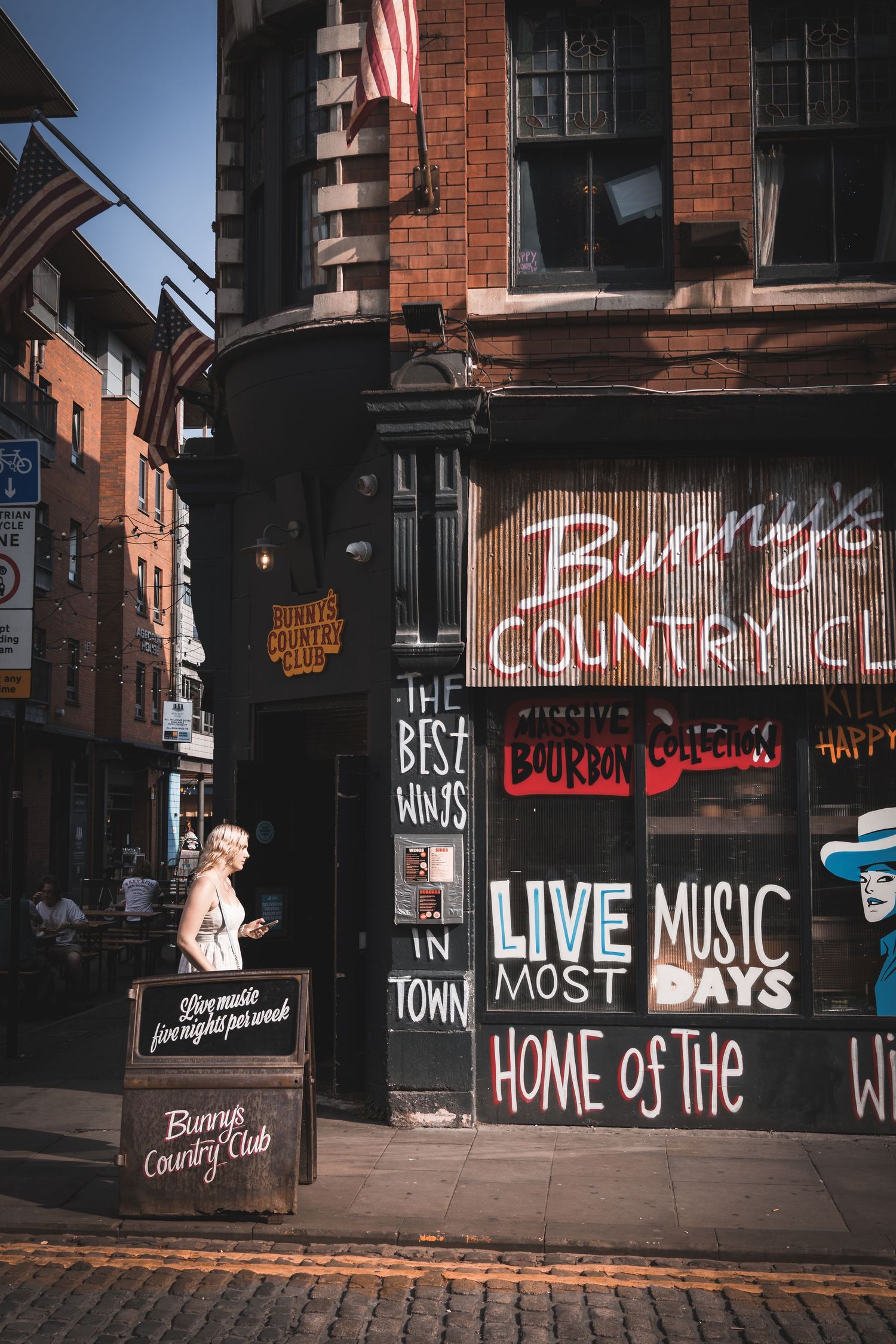 Row of illuminated bar signs and neon text advertising live music and country club entertainment.