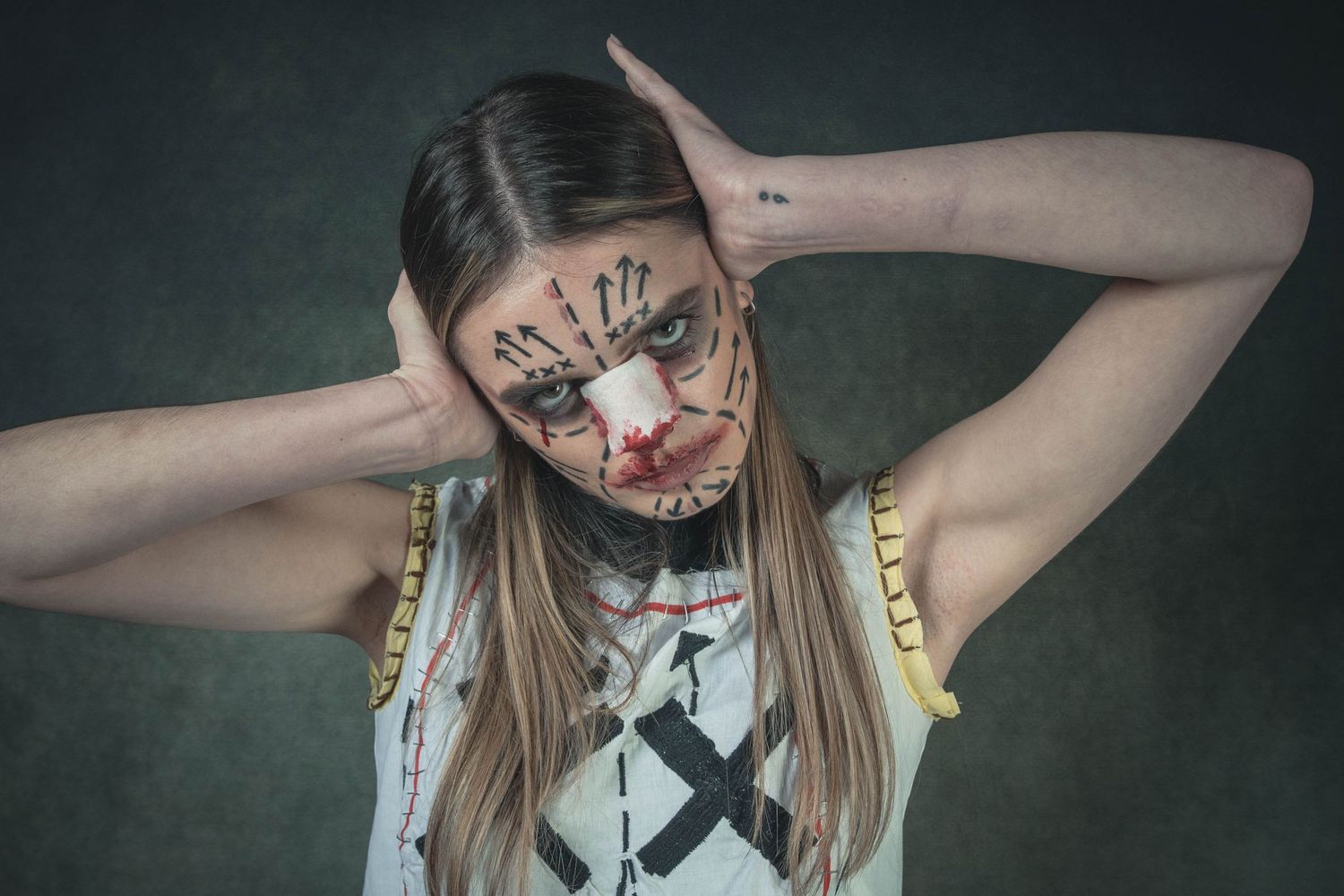 A person with long hair and dark makeup poses dramatically against a dark background in a gothic style photo series.
