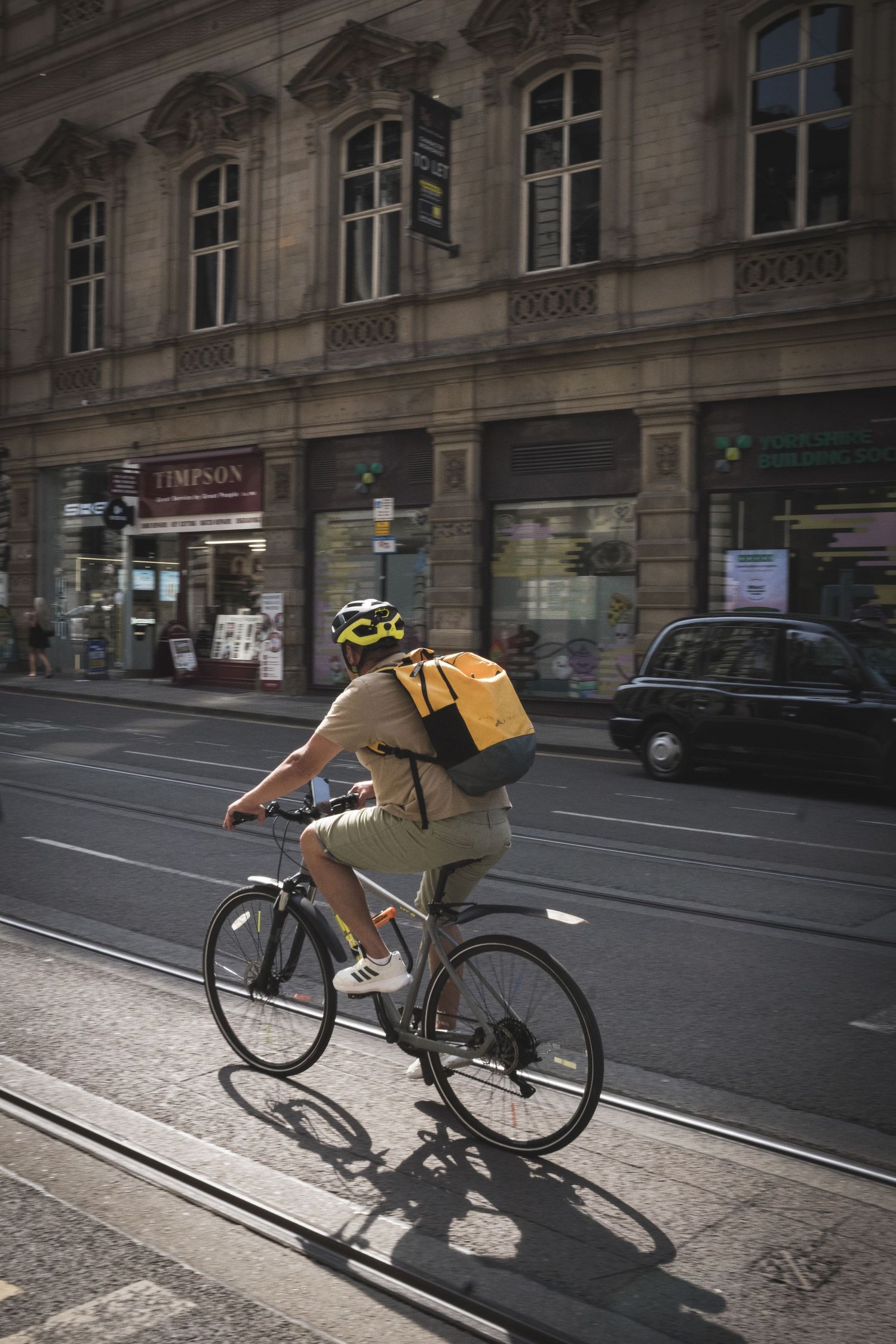 A series of images showing a delivery cyclist leaning into turns while riding through a European city street.