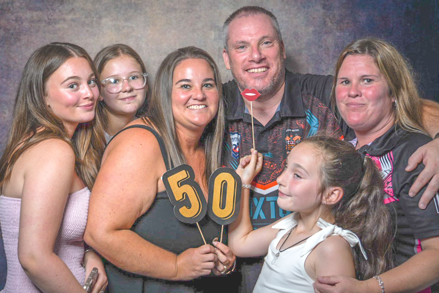 Group of people posing and smiling together at what appears to be a casual social gathering or party.