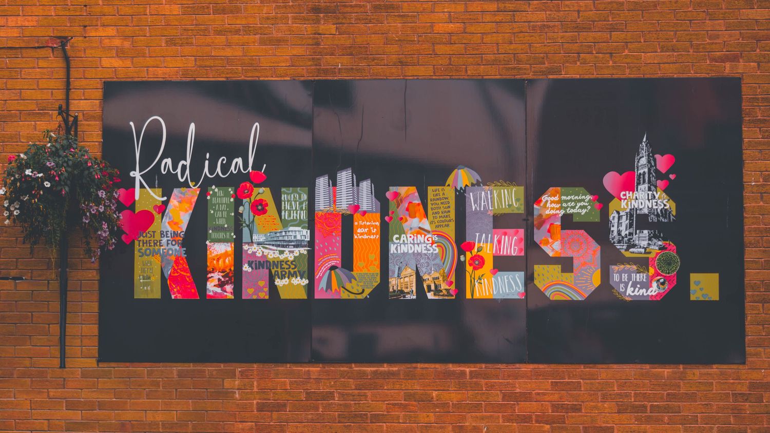 A panoramic view of colorful graffiti text art on a long brick wall with vibrant lettering against red bricks.
