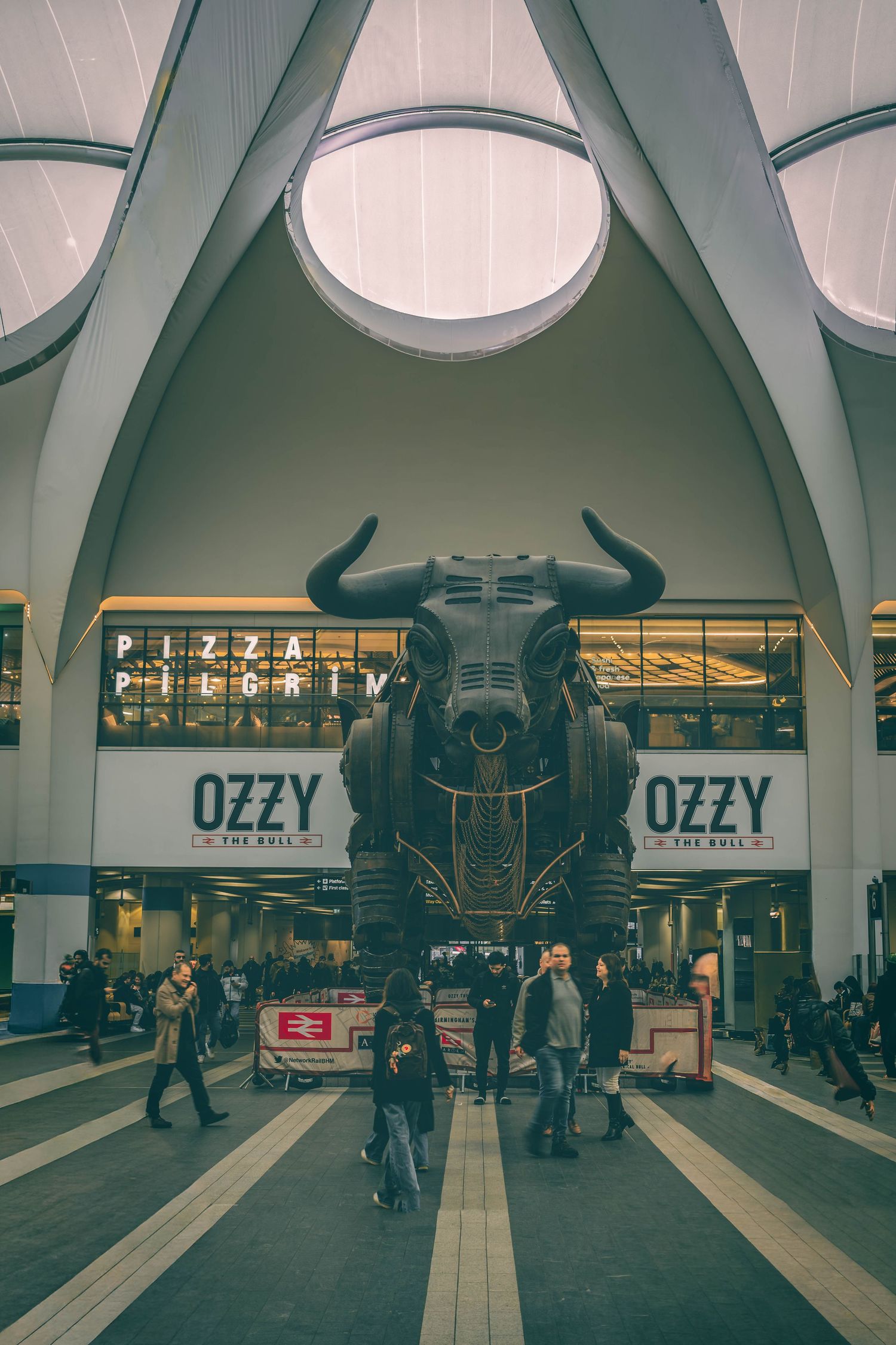 Interior view of a modern subway station with circular ceiling lights and 'OZZY' signage visible in multiple frames.
