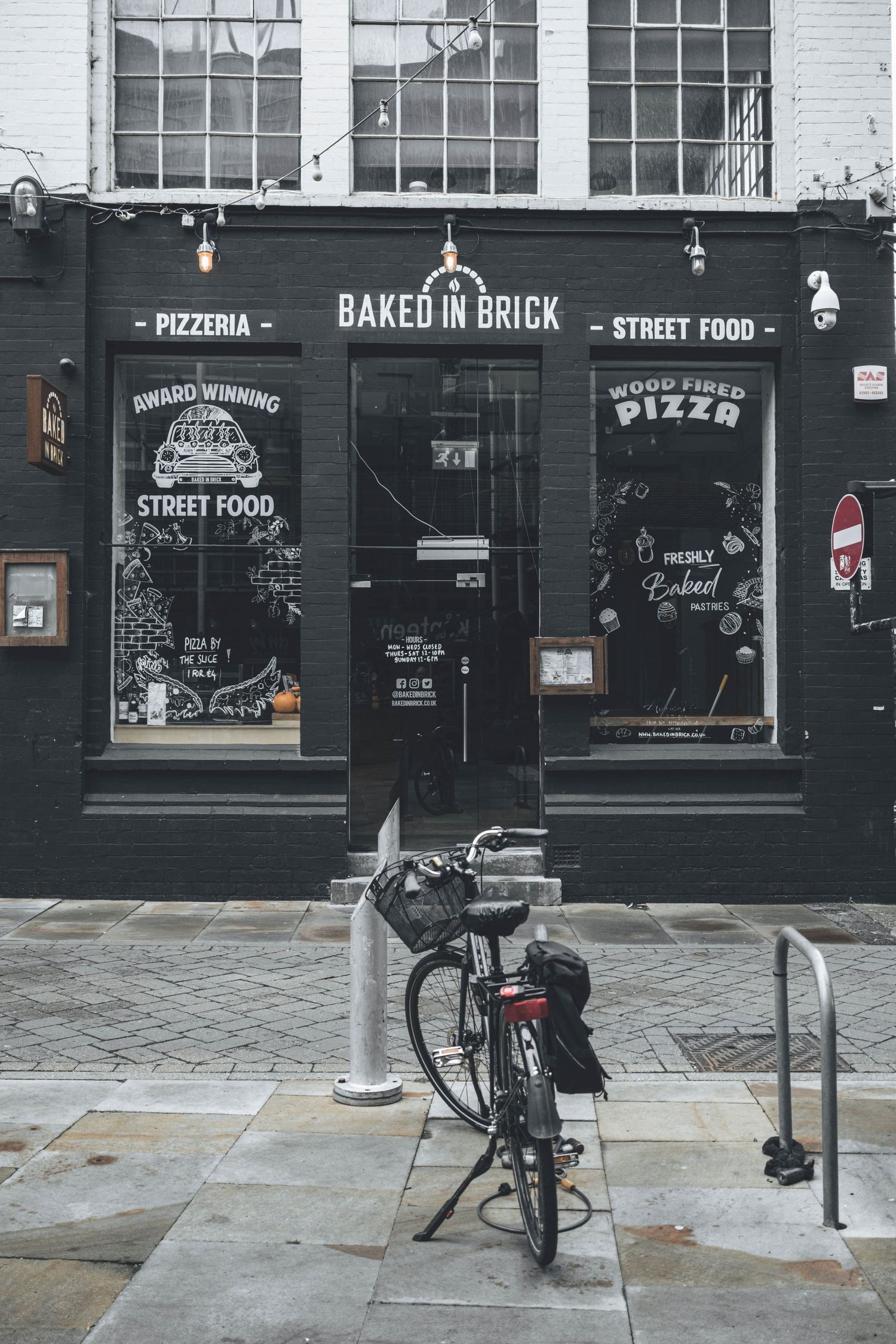 Delivery bicycle parked outside a brick pizzeria storefront with 