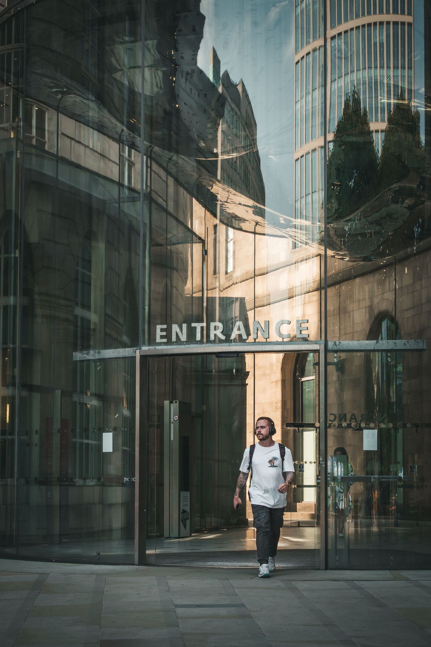 Modern glass building entrance with reflective surfaces and geometric architecture in downtown setting.