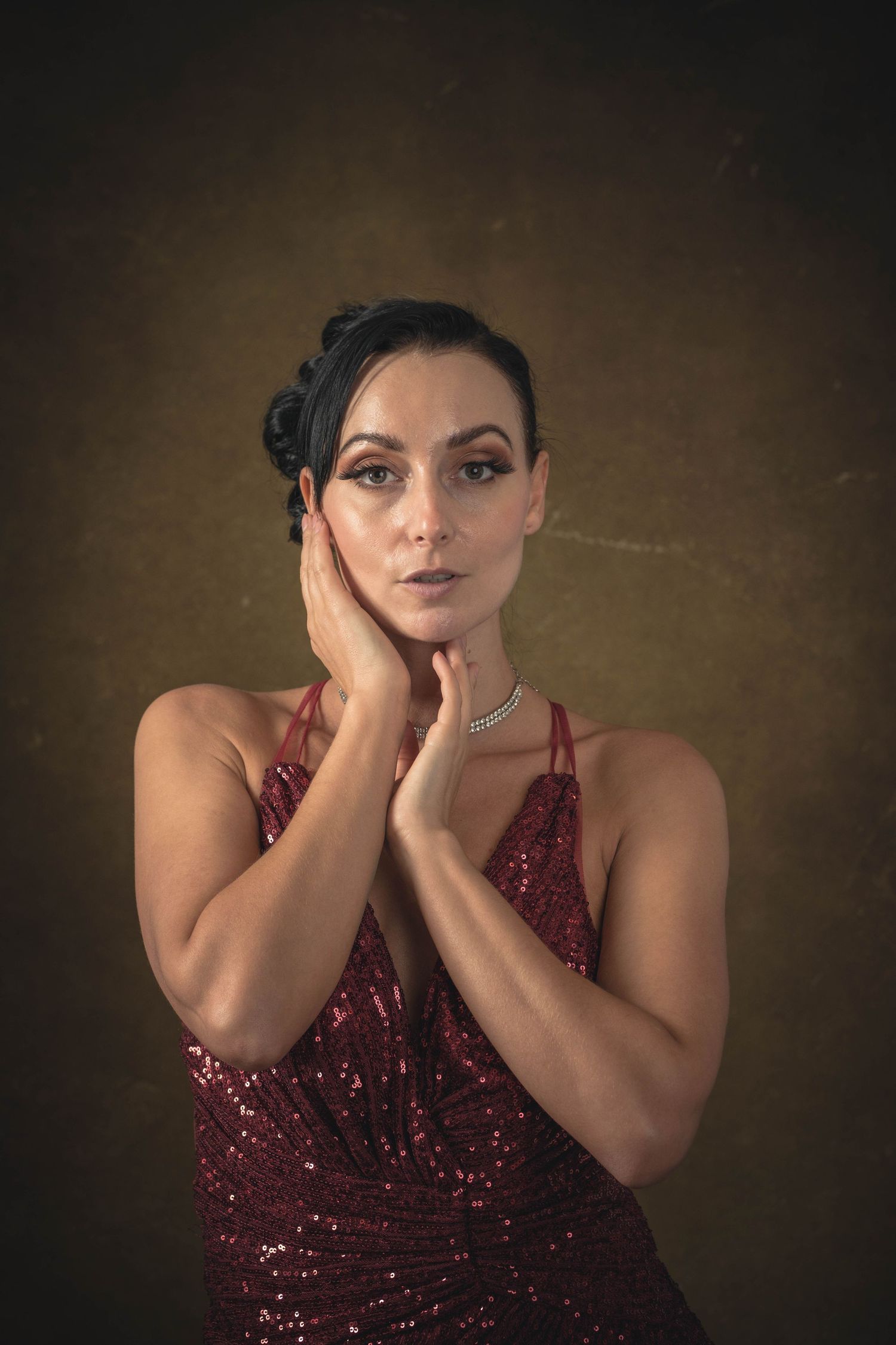 A person in a burgundy sequined dress poses expressively against a dark background in a photo series.