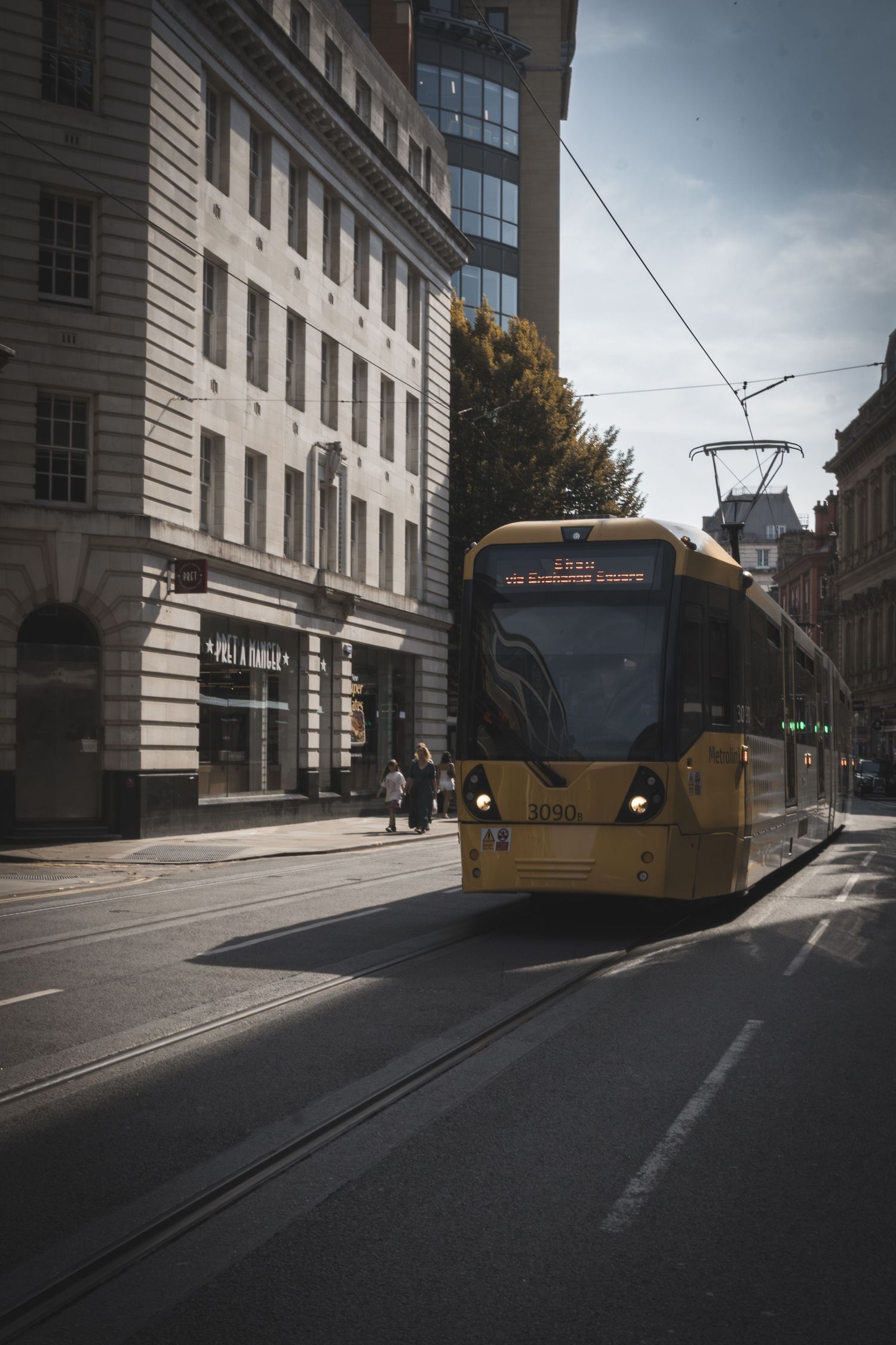 A sequence of five frames showing a yellow tram moving along a street in an urban setting with stone buildings.
