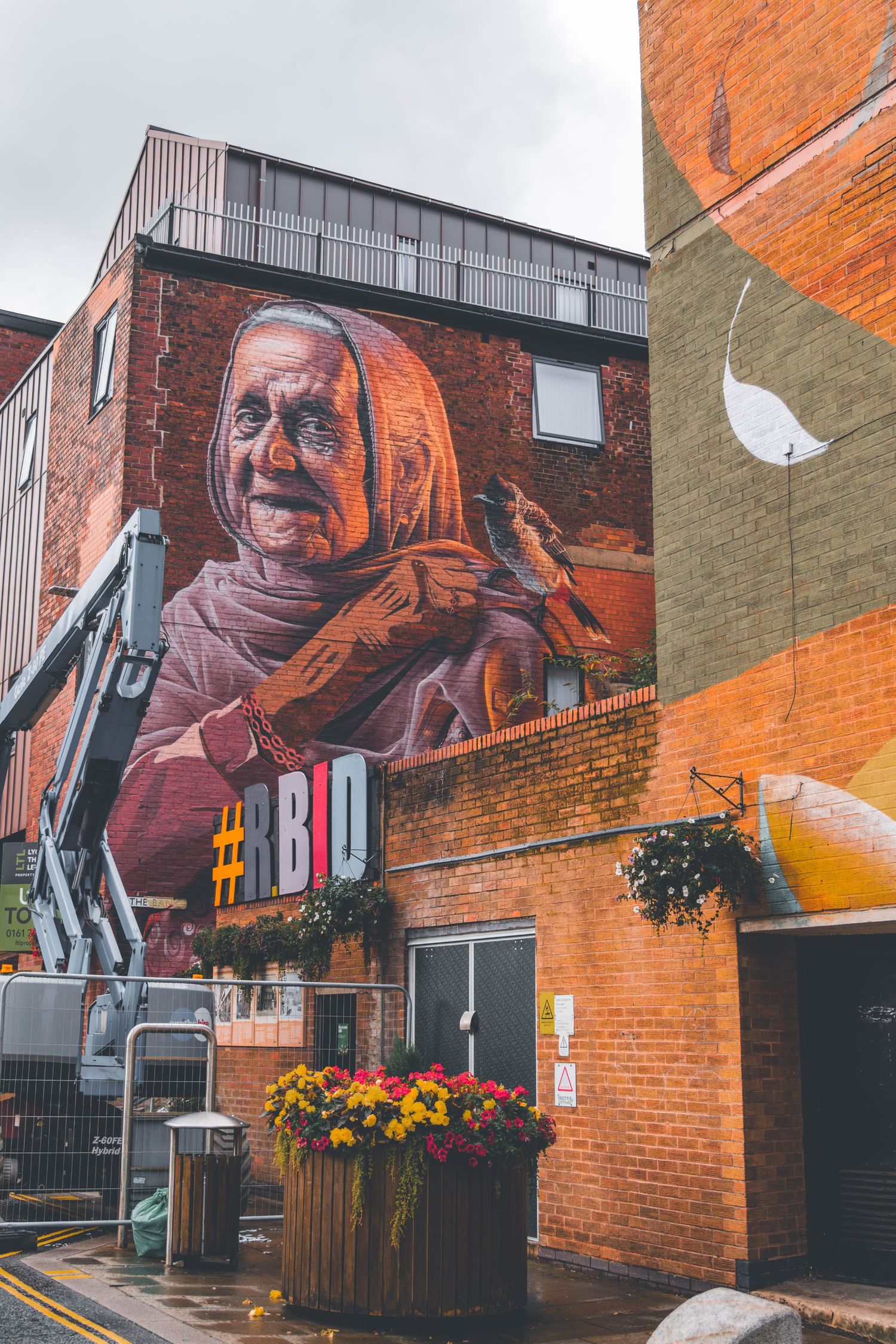 Large colorful street art murals painted on brick buildings with orange and gray walls create an urban art gallery atmosphere.