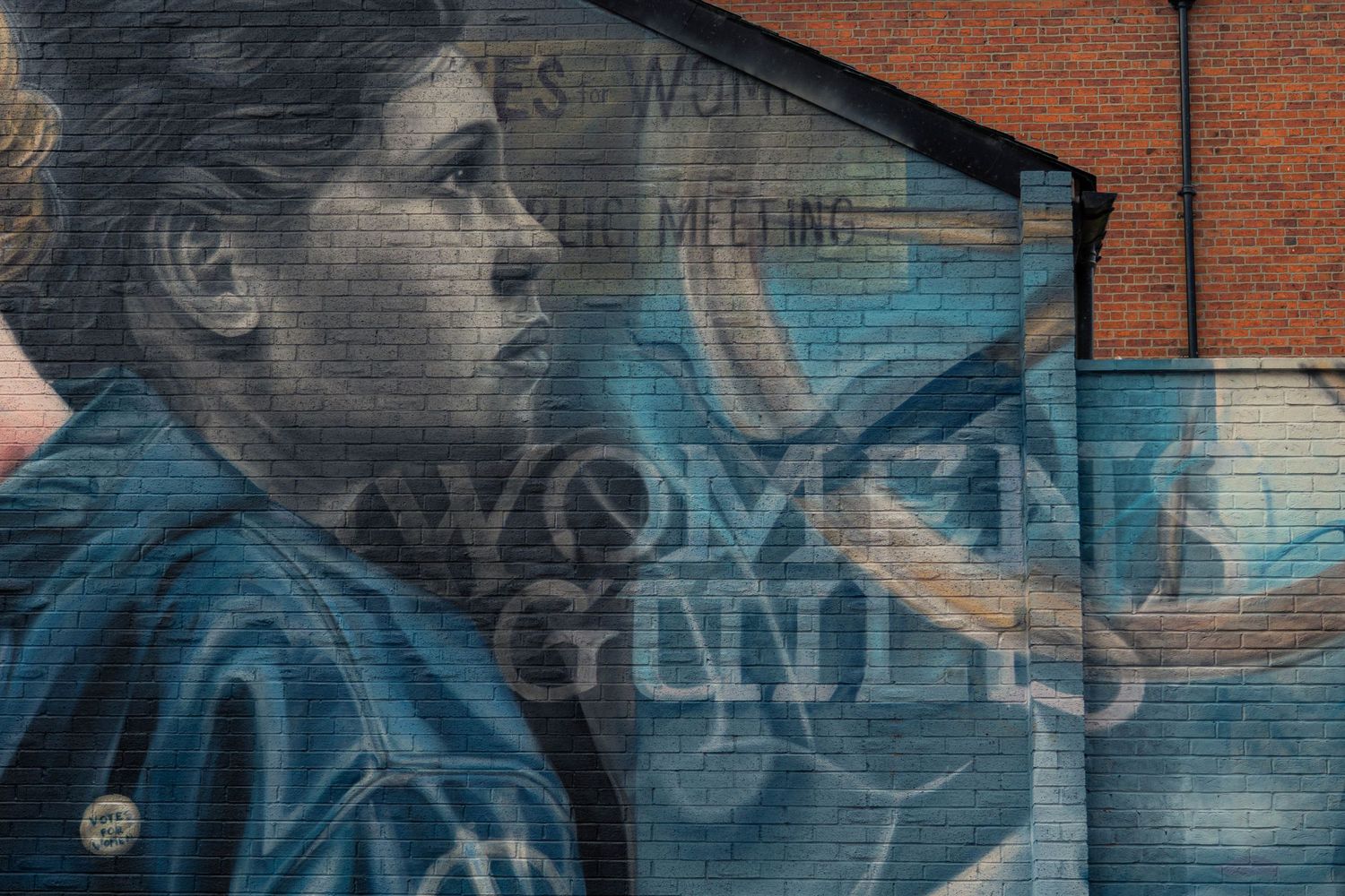Colorful graffiti art with blue and gray tones covers a brick wall in an urban setting.