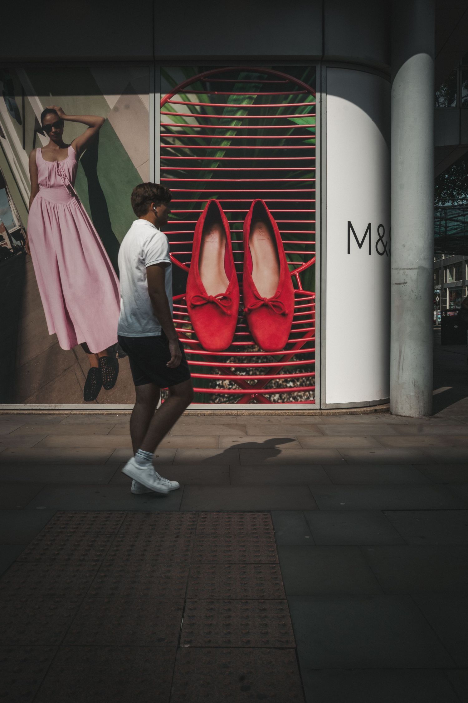 Storefront with red and pink clothing visible through partially closed security shutters.