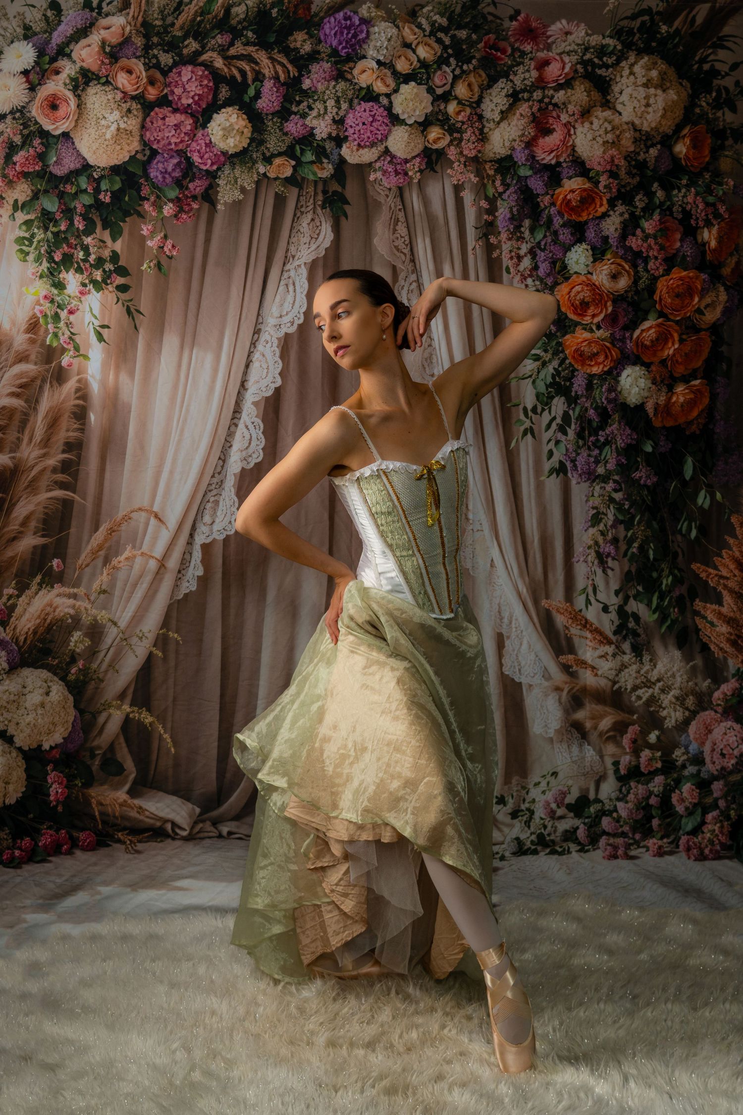 Ethereal dance portrait with flowing green dress against floral wall backdrop.