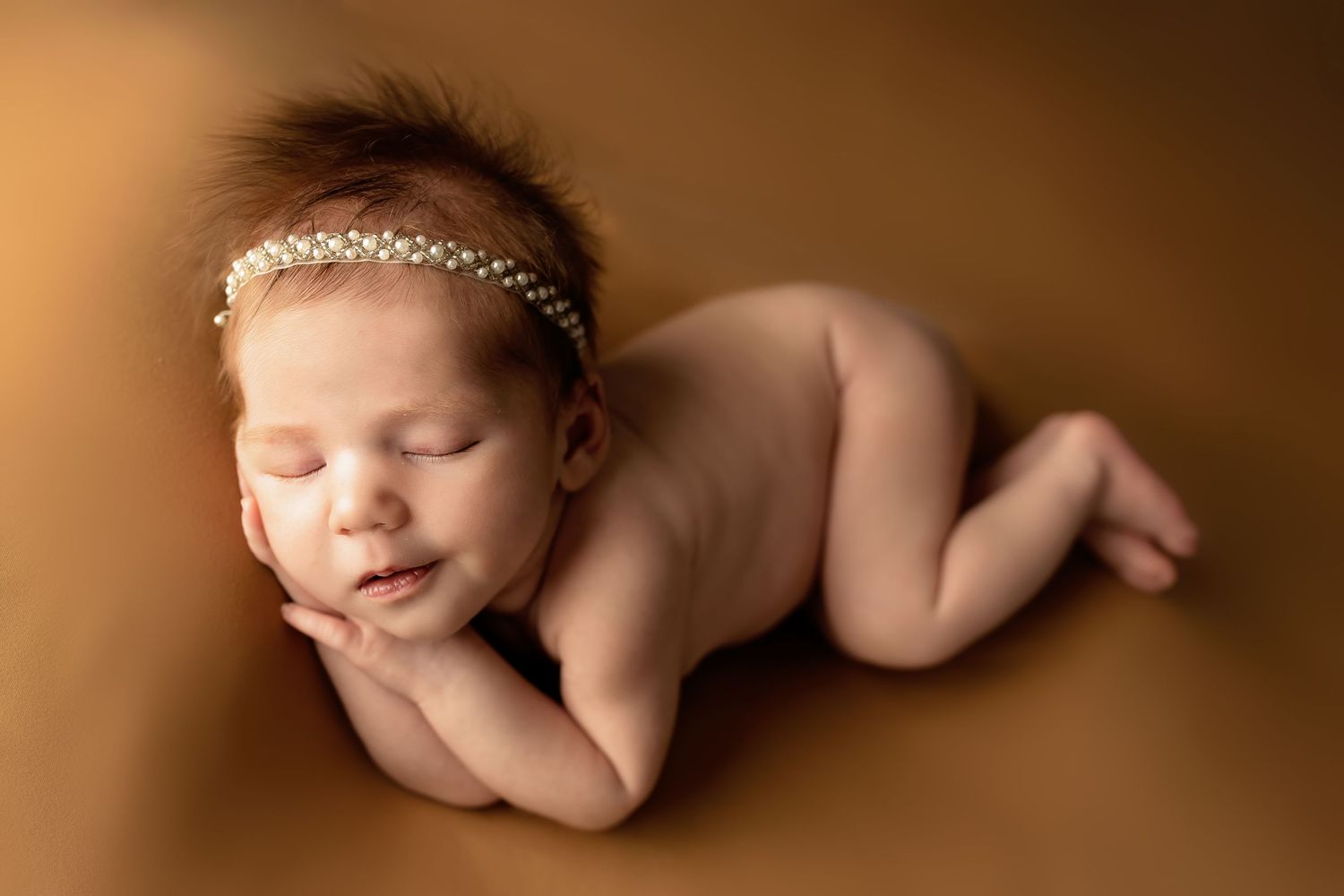 A collection of artistic sepia-toned newborn portraits against a brown backdrop.