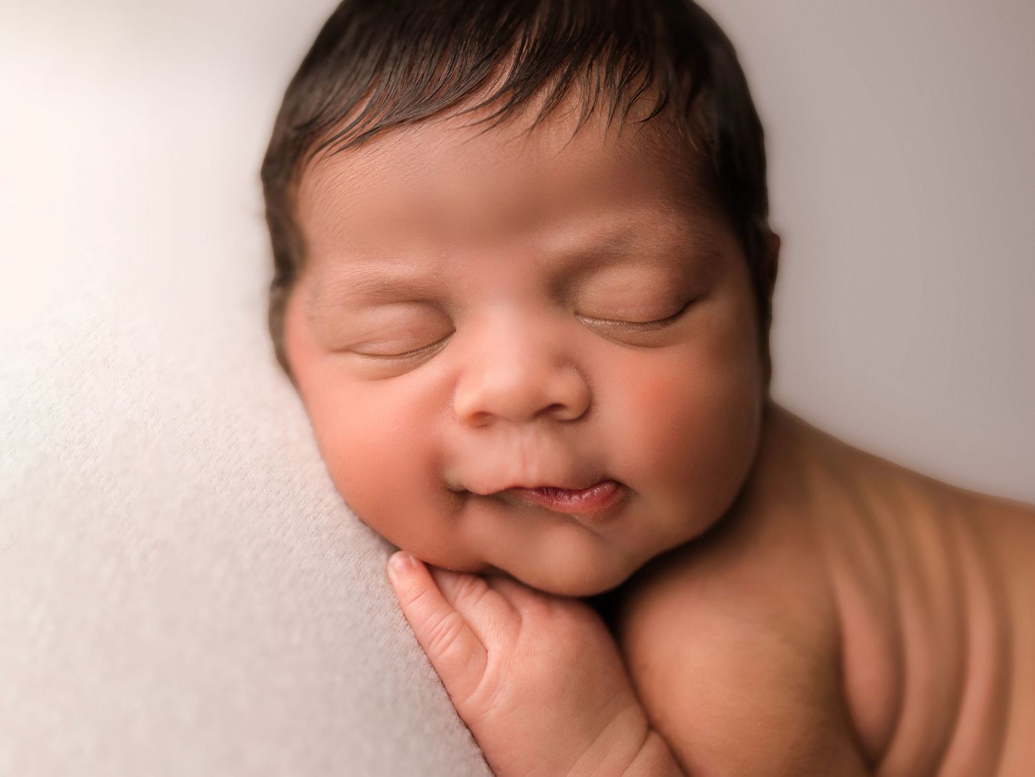 Professional studio portraits showing peaceful sleeping baby with dark hair.