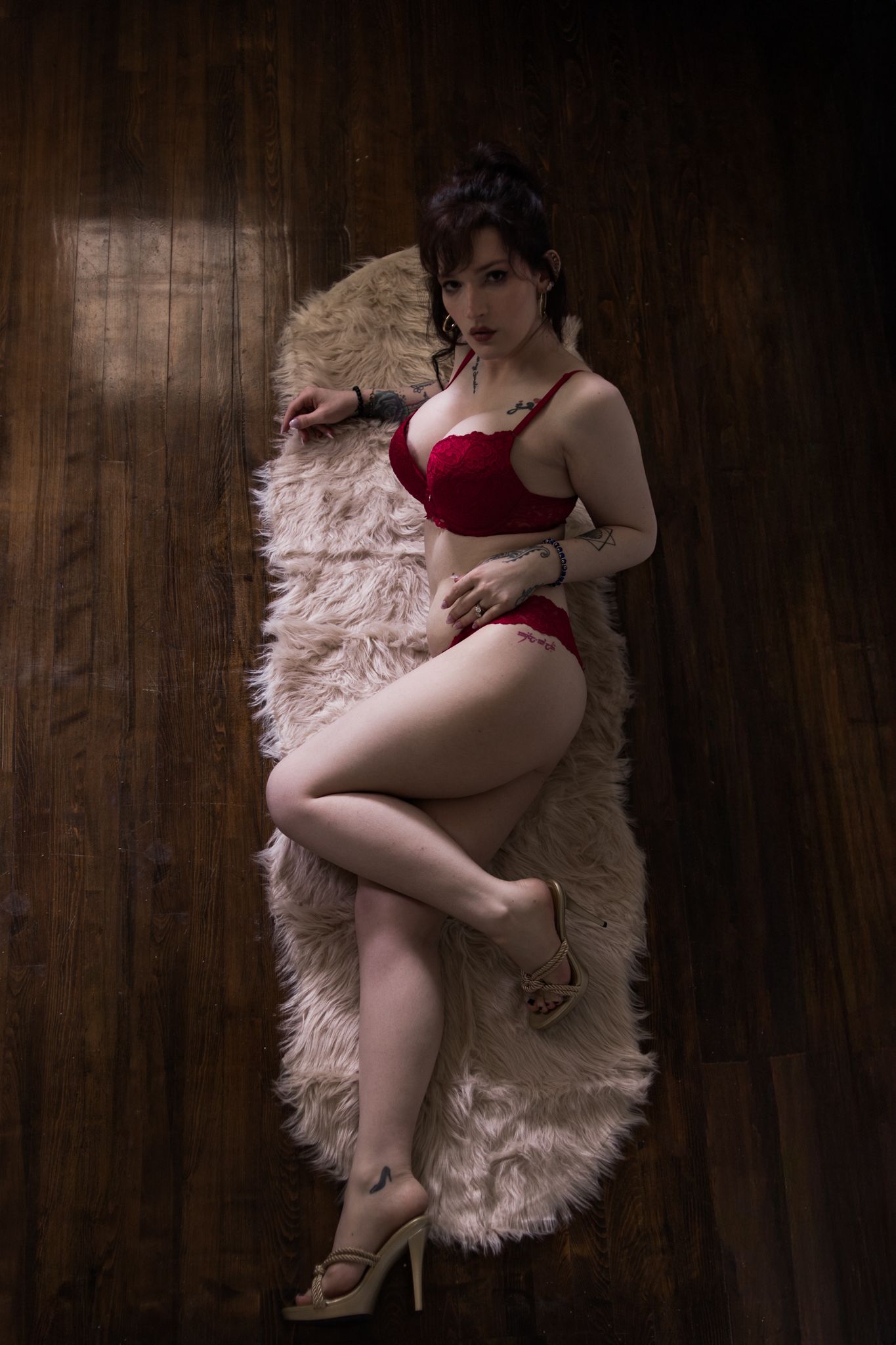 A sensual boudoir photoshoot series featuring red lingerie and a fluffy white rug on dark hardwood flooring.