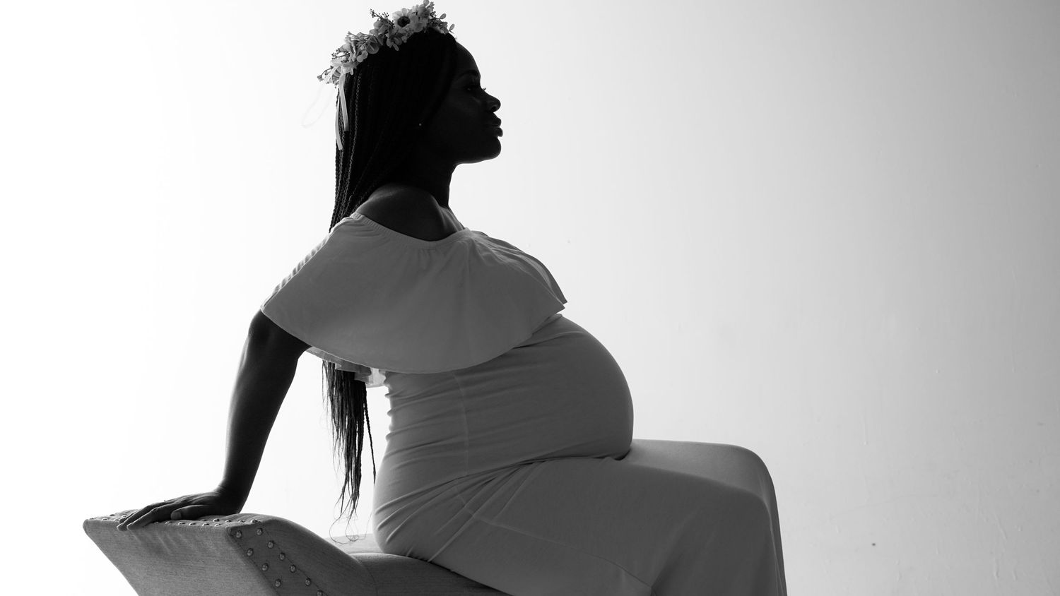 Silhouetted black and white profile of a pregnant woman stretching backwards in contemplative pose.