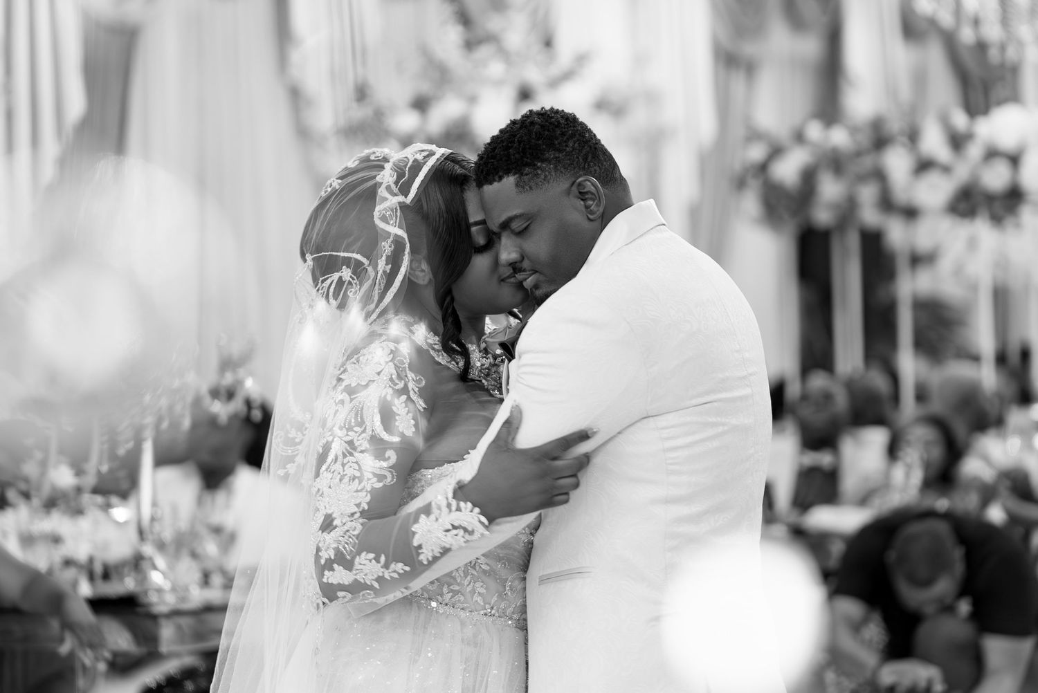 A tender moment captured in black and white between newlyweds during their first dance at an elegant wedding reception.