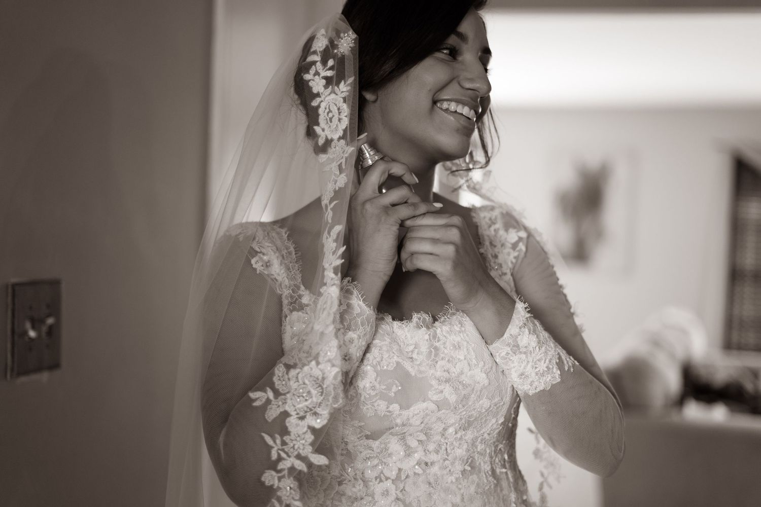 A bride adjusts her delicate lace wedding gown sleeve while preparing for her special day.