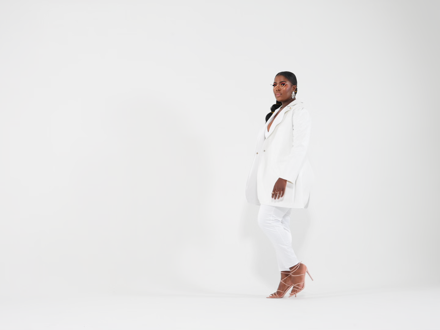 A figure in a white robe performs a fluid dance movement against a stark white background.