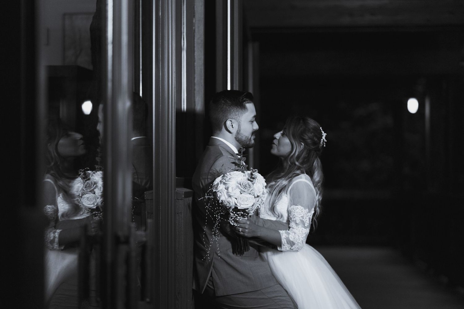 A romantic couple shares a tender moment during their wedding dance, captured in black and white photography.