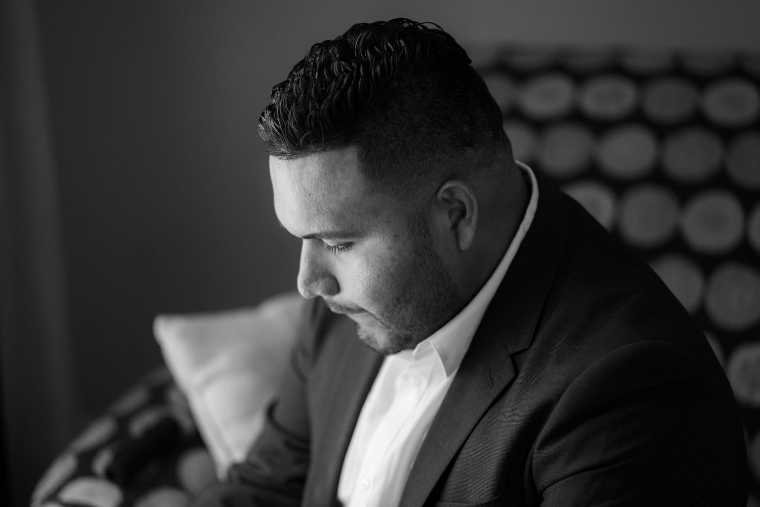 Black and white profile portrait of person wearing a suit jacket and white shirt in contemplative pose.