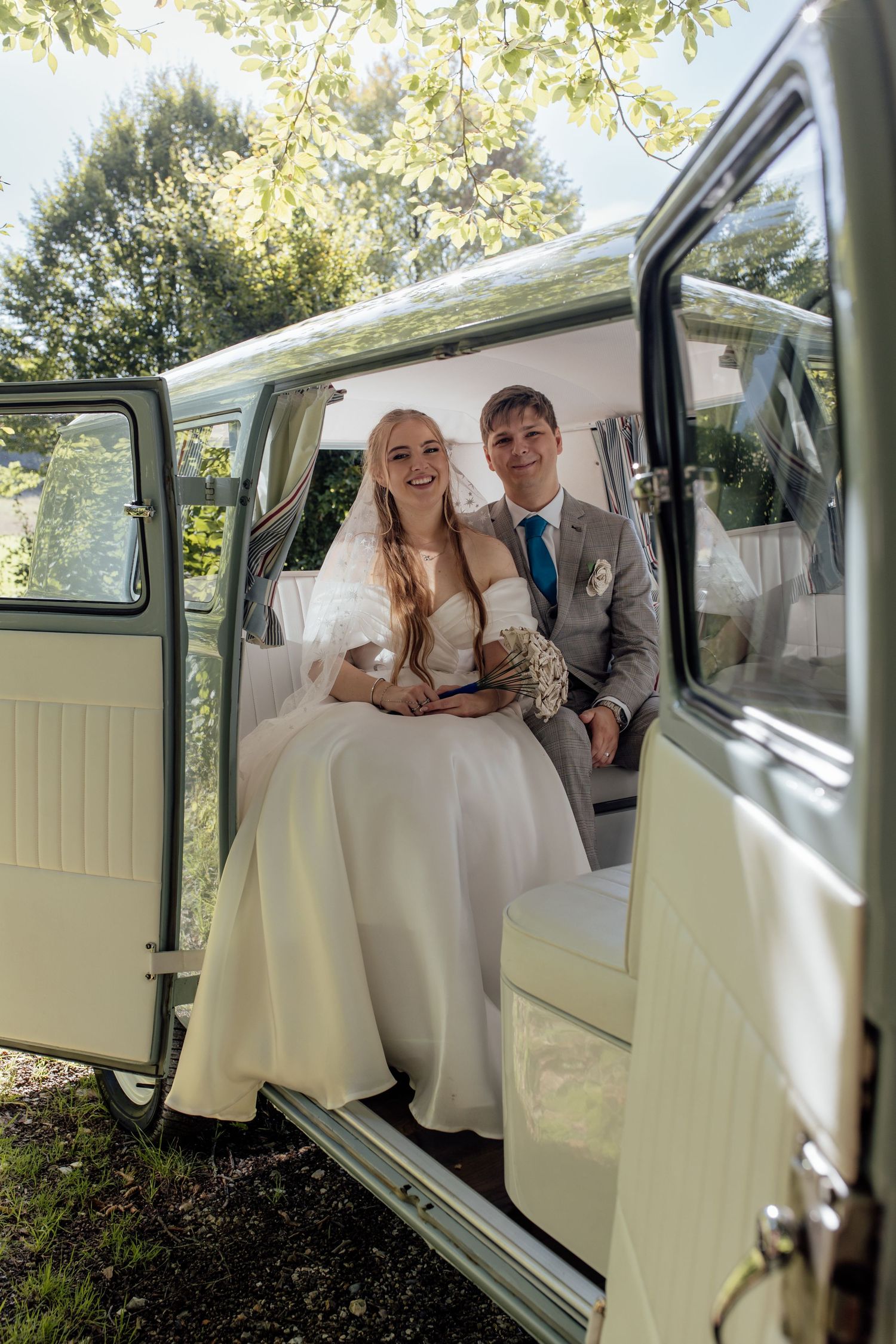 A bride and groom share intimate moments in a classic white vintage car during their wedding photoshoot.