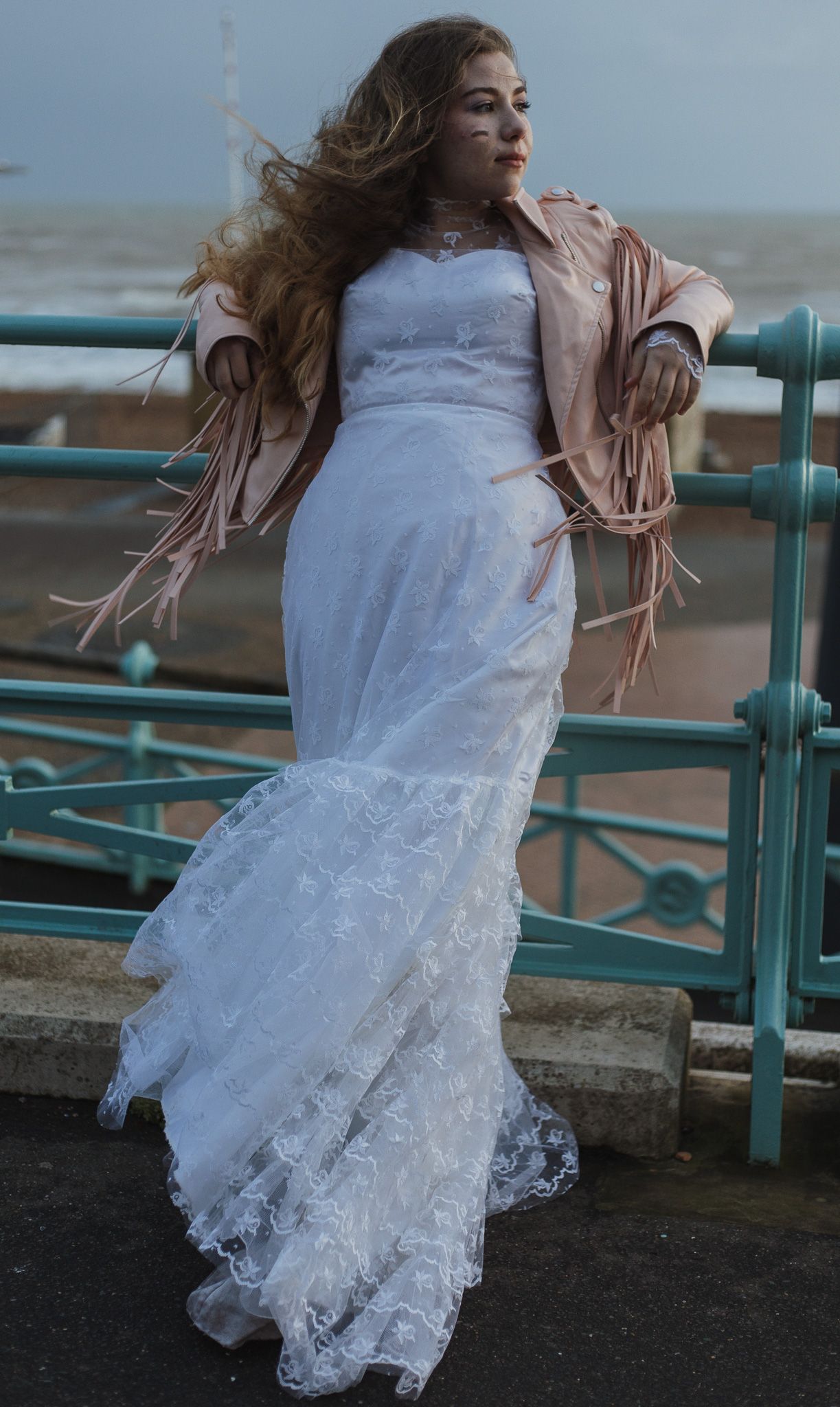 Eight sequential photos show flowing white dress and hair movement against a seafront railing at dusk.