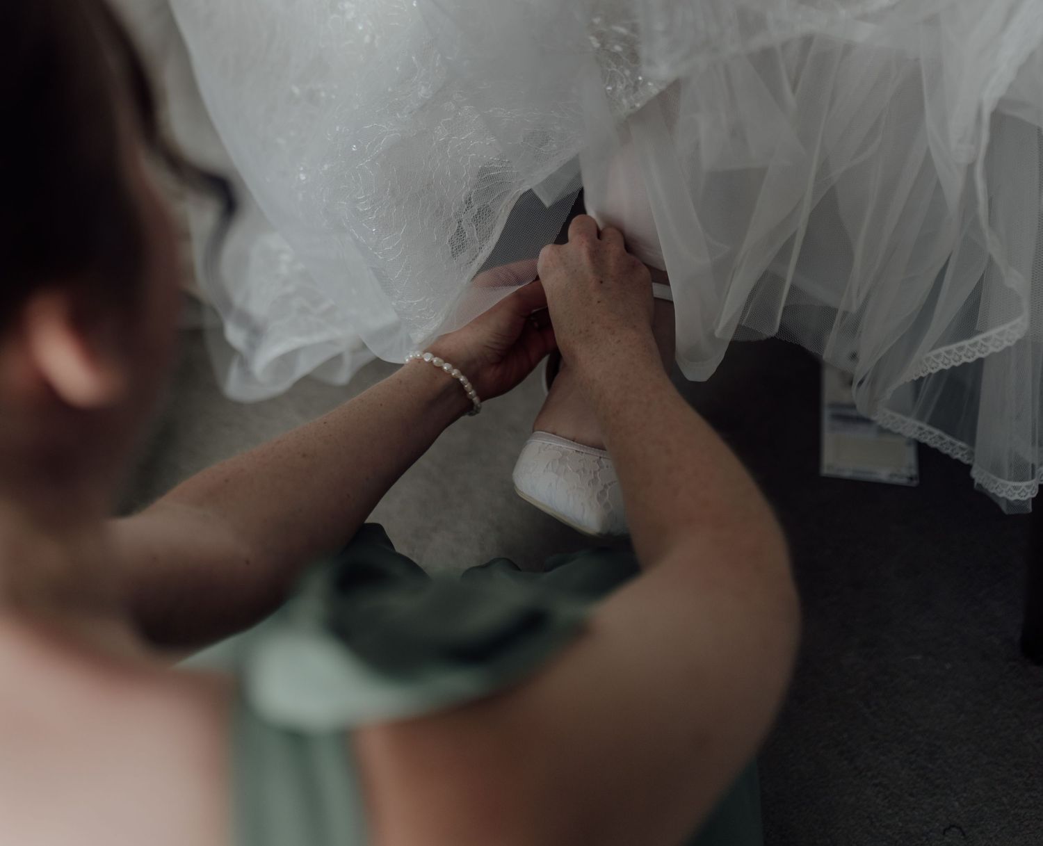 A close-up sequence showing hands delicately adjusting a white tulle veil or fabric in soft lighting.
