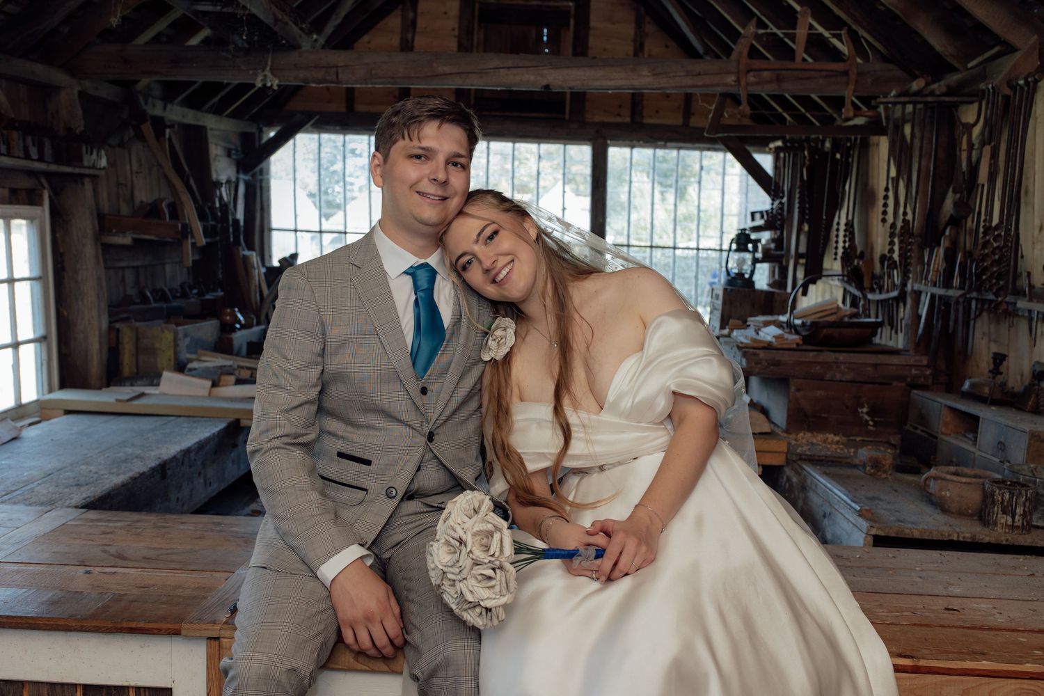 Wedding couple sharing intimate moment in rustic barn setting with natural lighting.