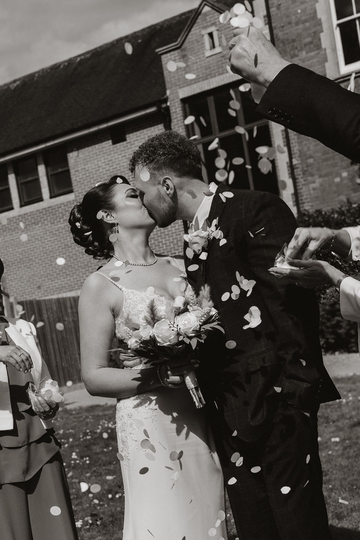 Bride and groom kiss during confetti throw.
