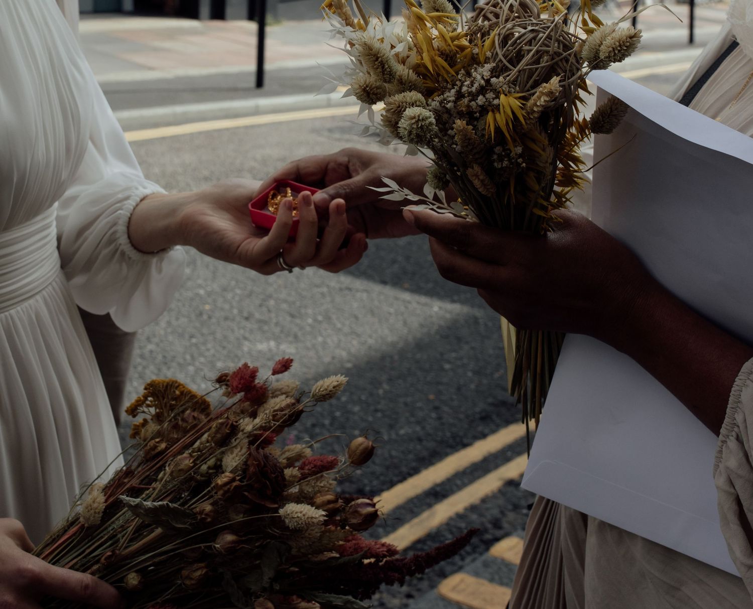 Close-up shot of hands holding a rustic autumn wedding bouquet with dried flowers and natural elements.