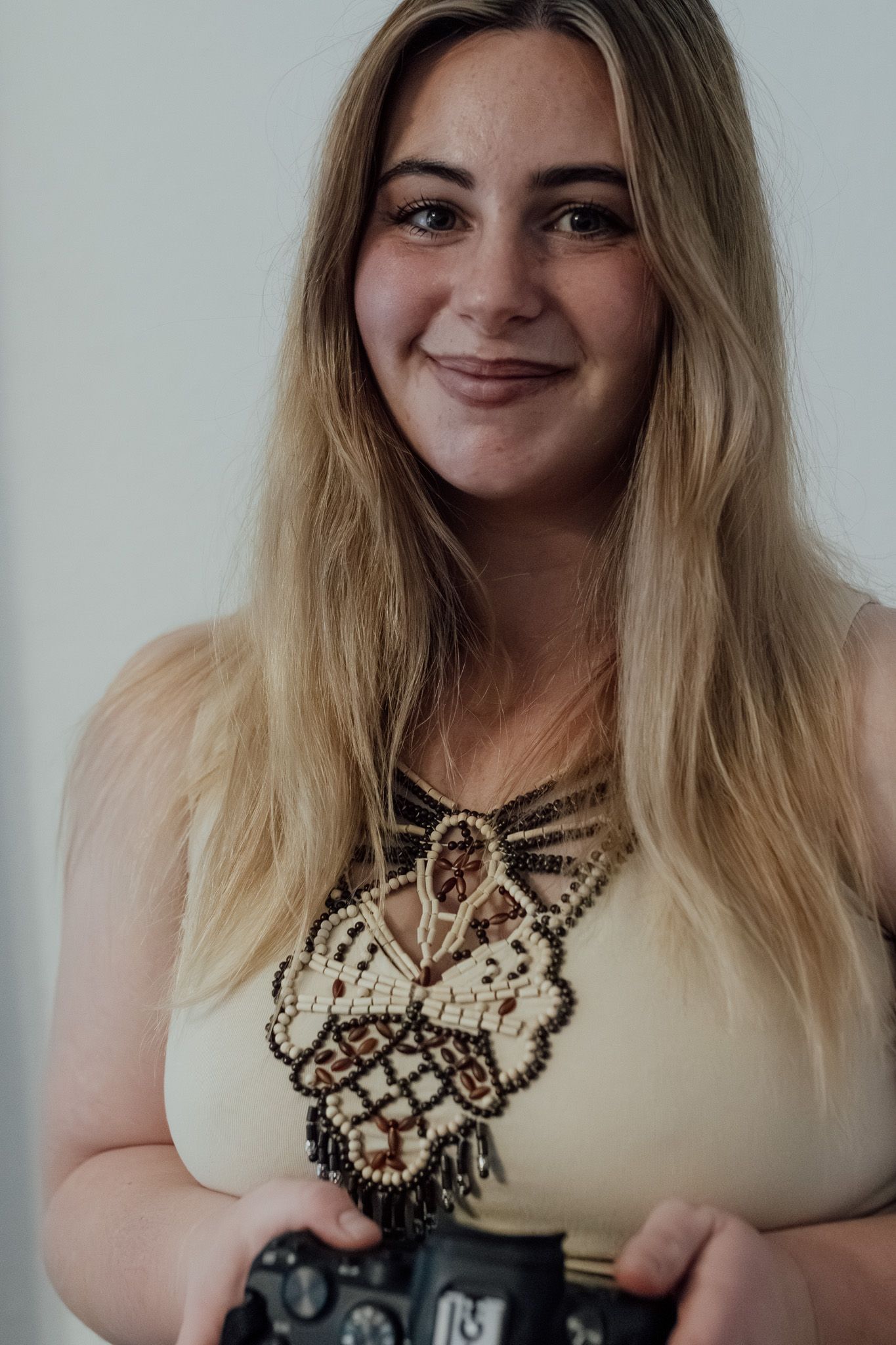 A person wearing a beaded statement necklace poses in a series of expressive selfie photos.