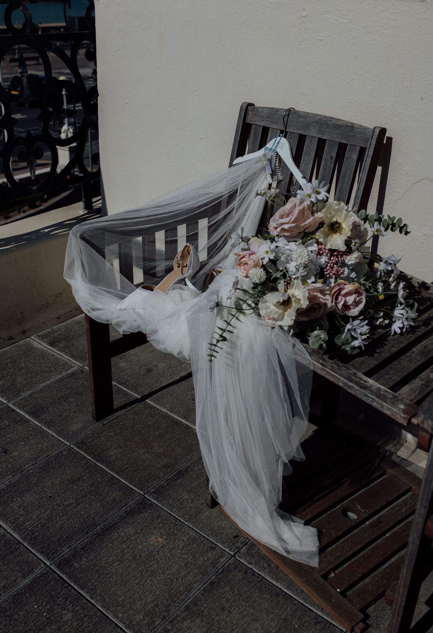 A series of photos showing a white wedding dress and floral arrangement displayed on a dark wooden bench outdoors.