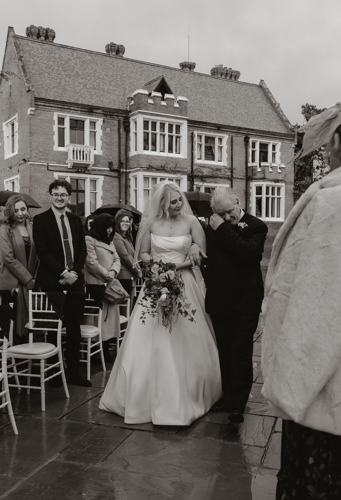 Black and white photo of wedding party dancing in reception venue.