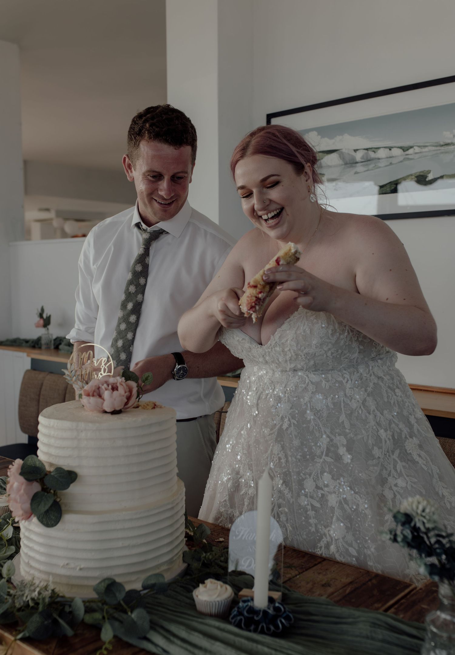 A couple cuts their elegant white wedding cake together in a series of candid moments during their reception celebration.