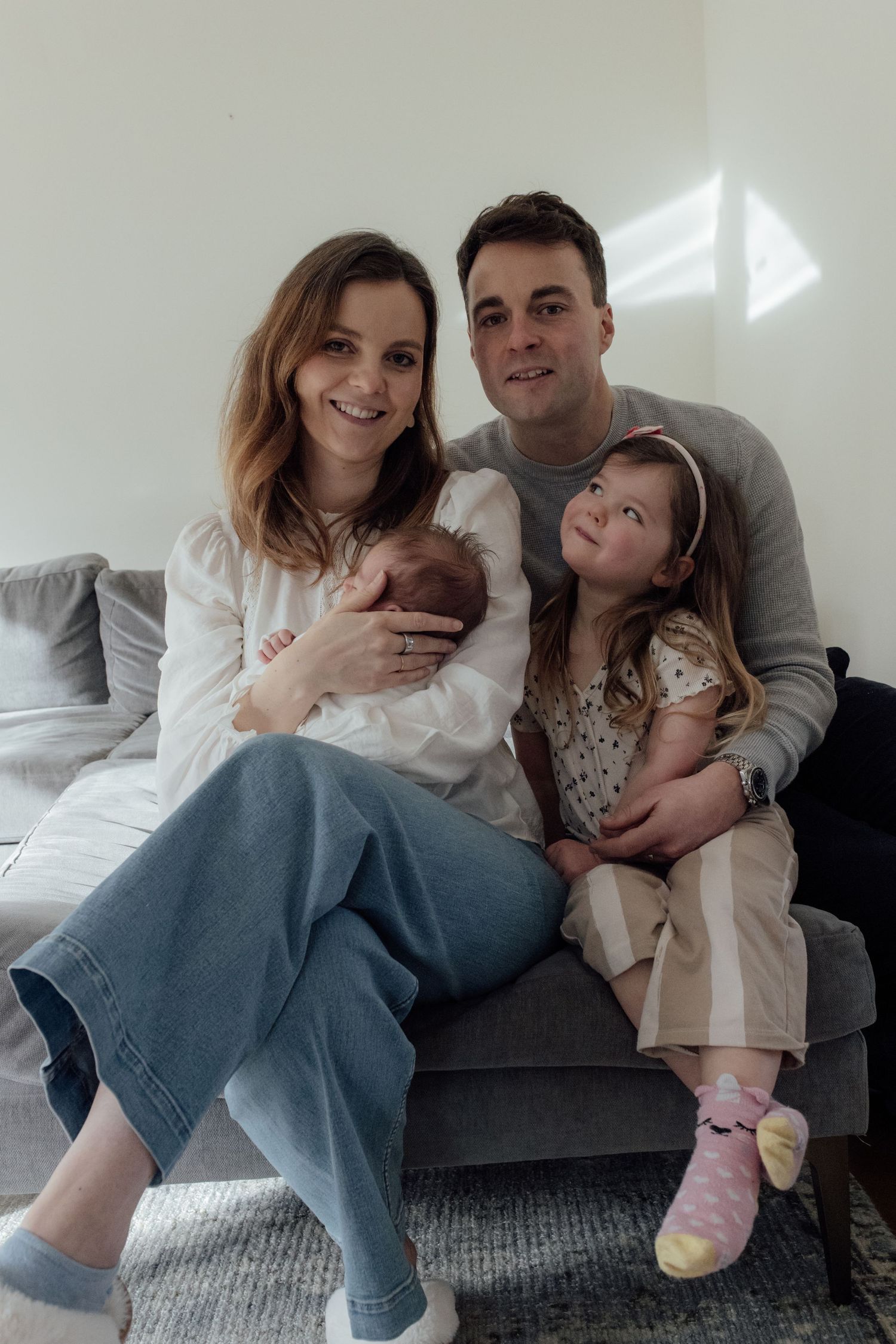 Family relaxing together on a gray couch in a casual home setting showing four candid moments side by side.