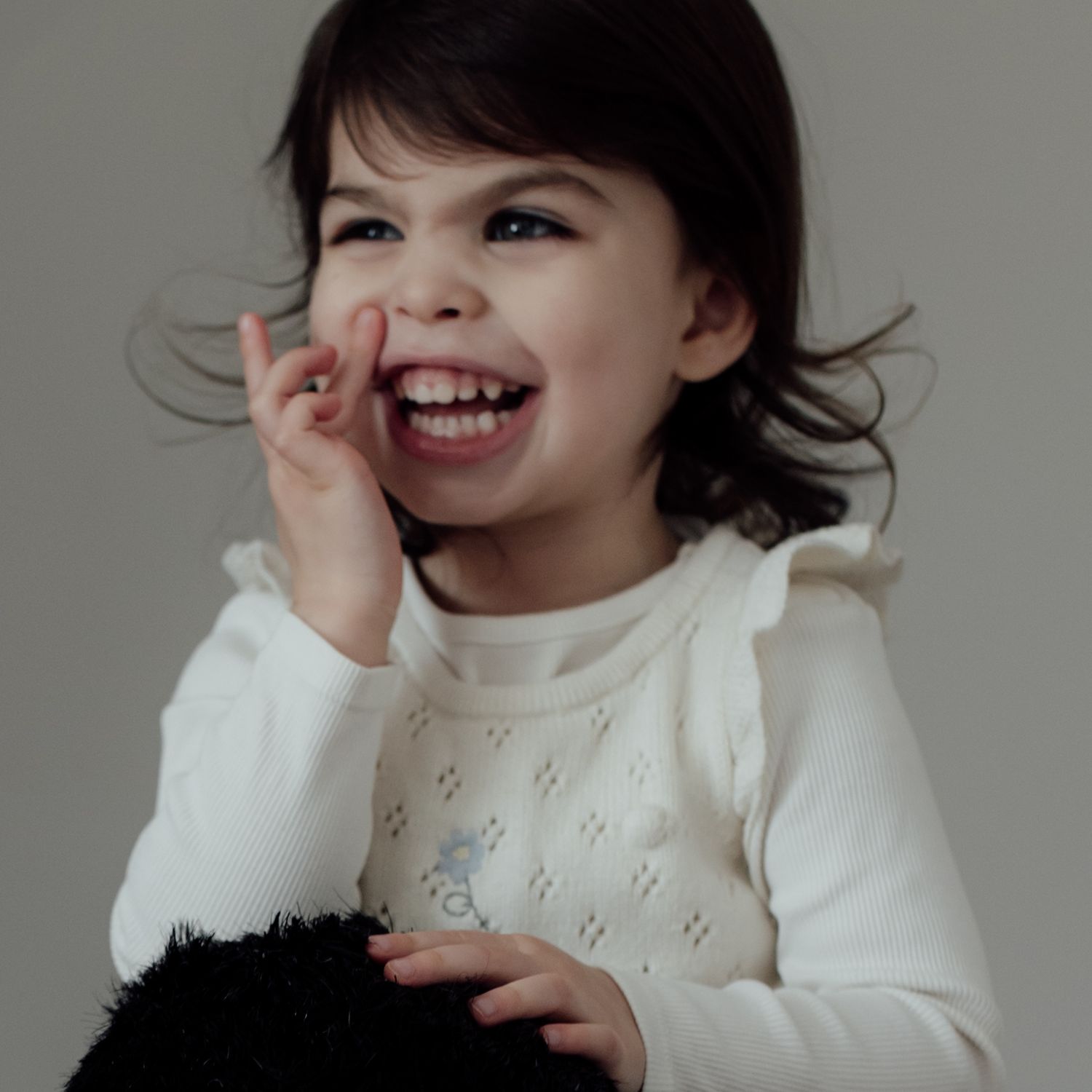 Person in white sweater laughing and posing playfully in a series of candid portrait shots.