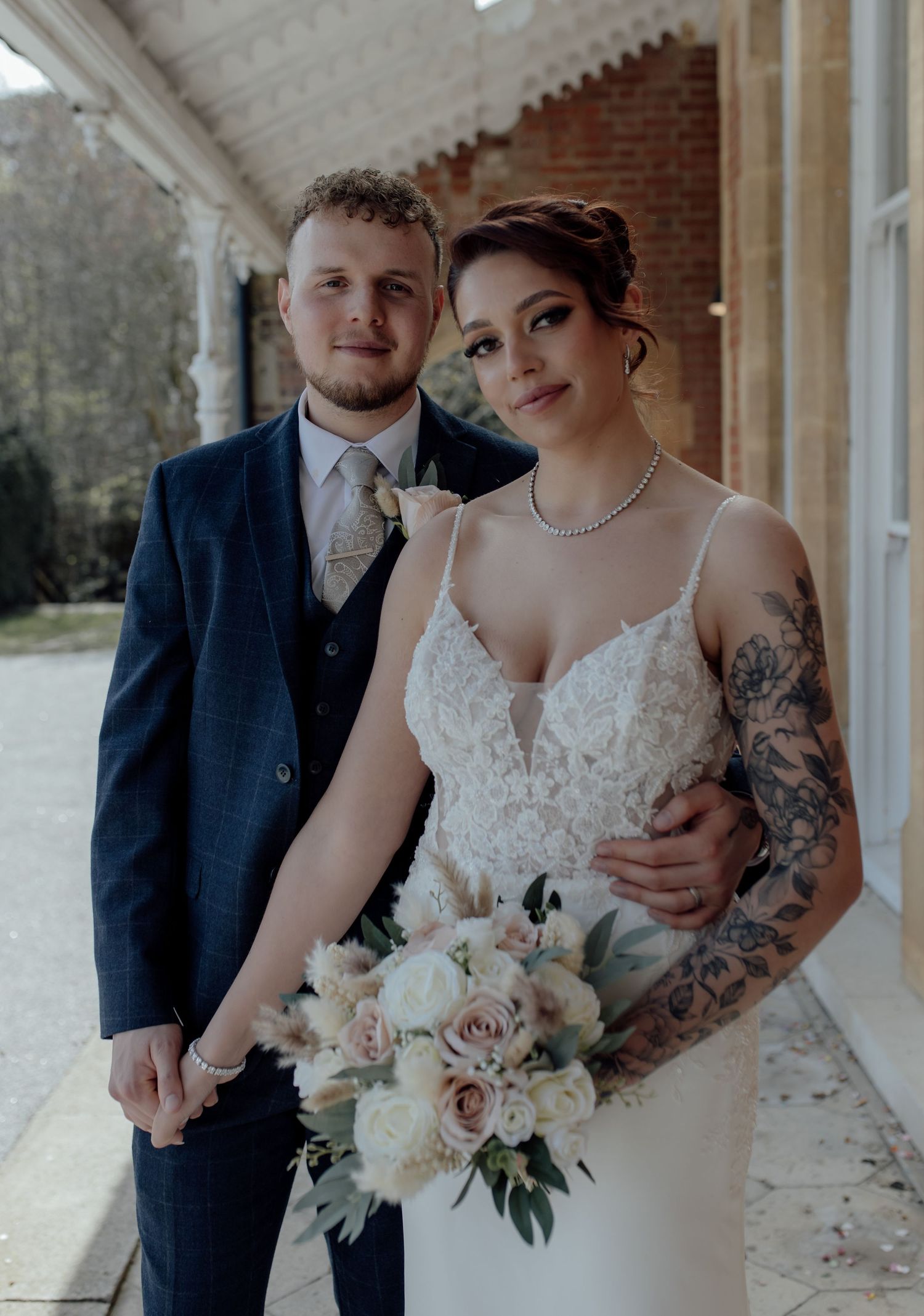 Bride and groom stand next to each other holding hands.