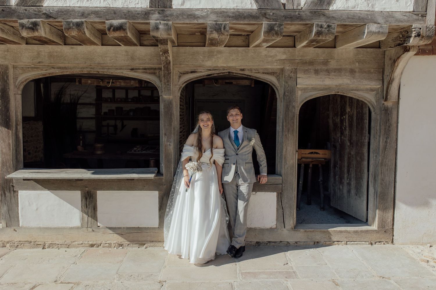 A bride and groom walk through an ornate stone archway during their wedding ceremony.
