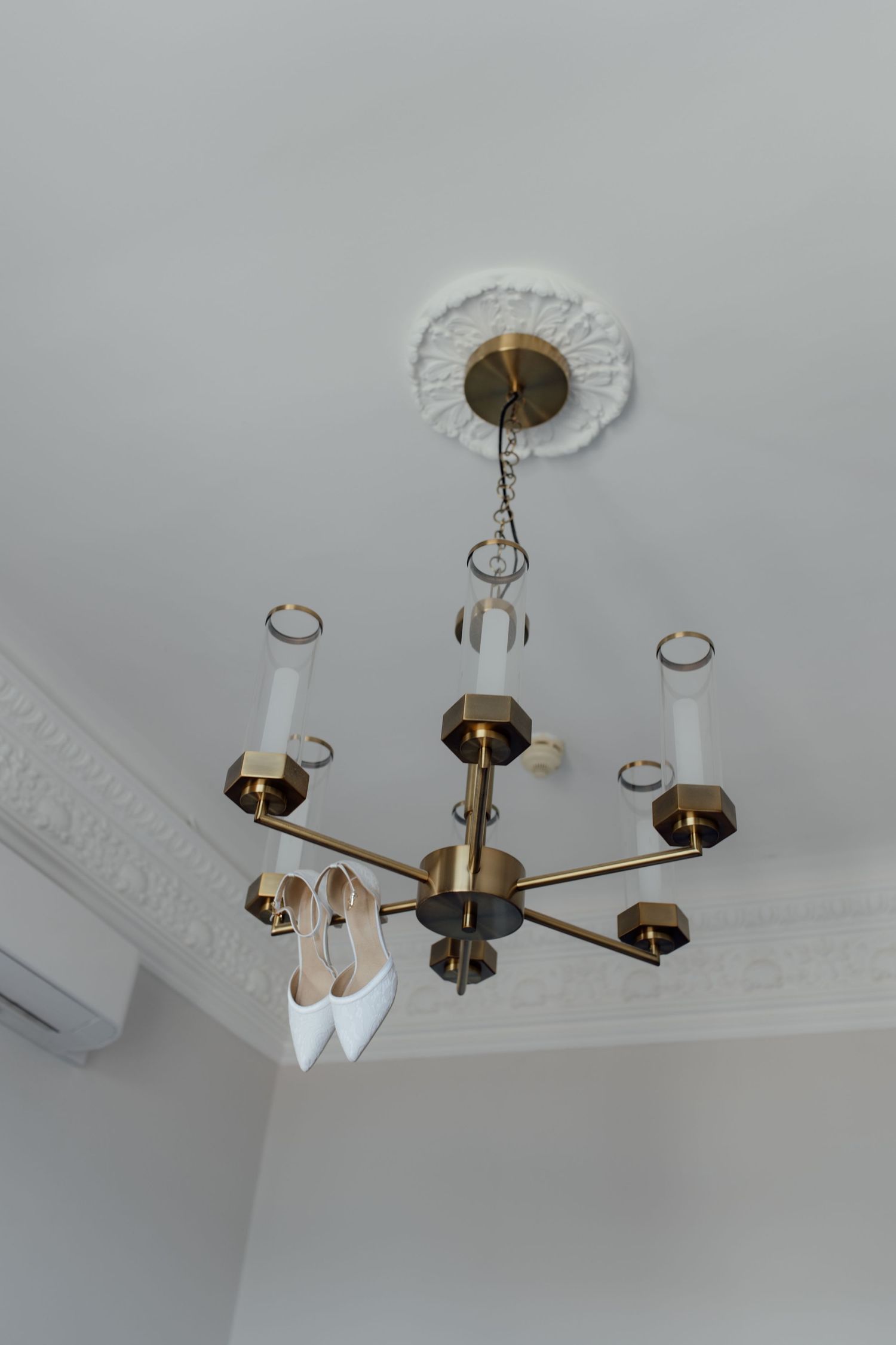 A series of photos showing the installation process of a modern brass chandelier with multiple arms on a white ceiling.
