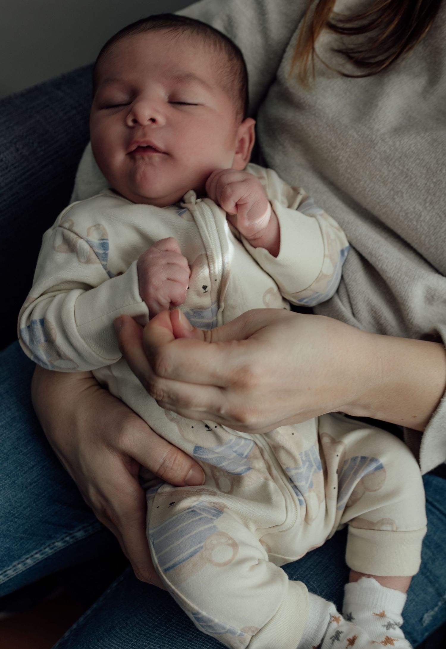 A sleeping baby in cream-colored clothing rests peacefully on soft bedding in a series of gentle poses.