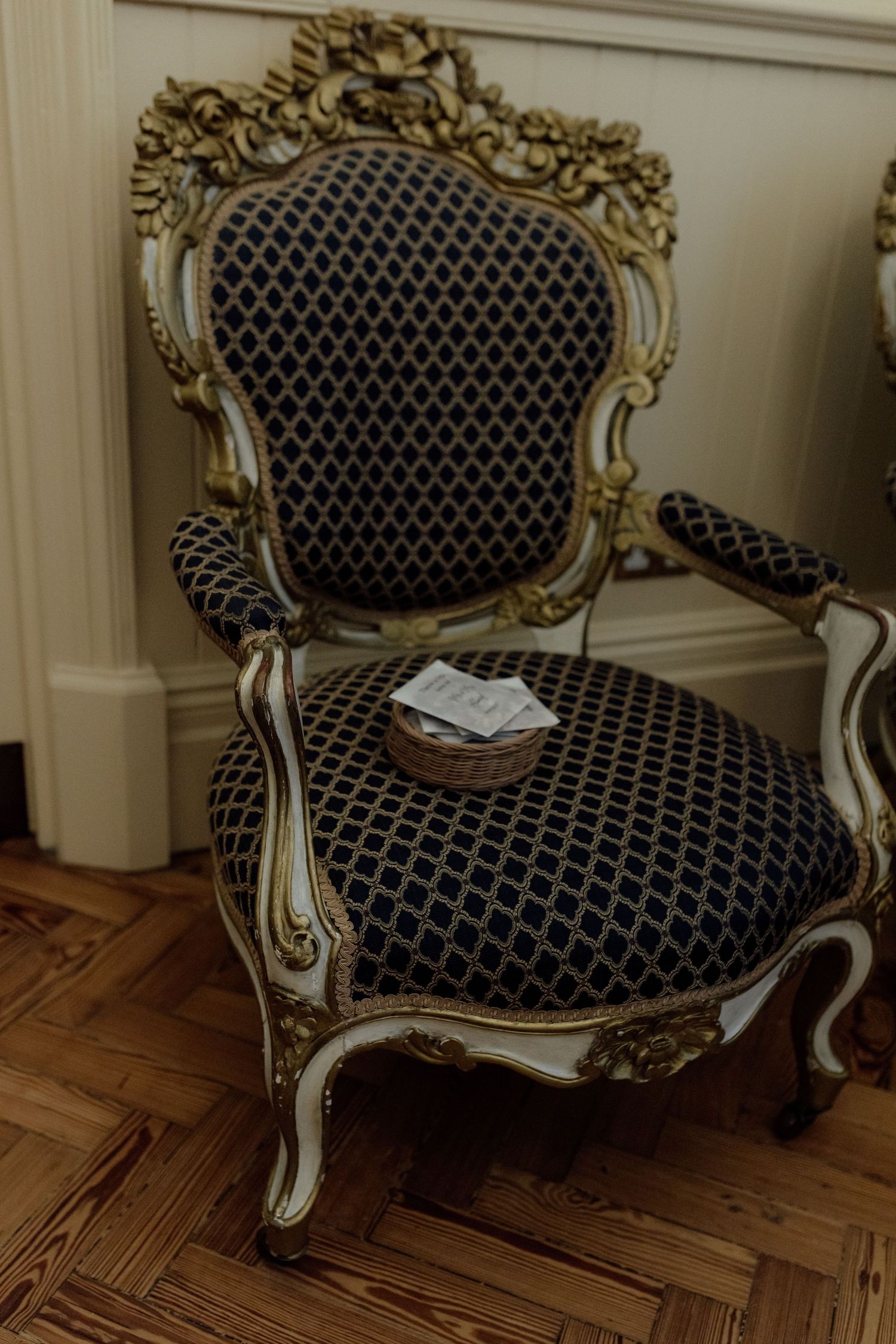 Ornate baroque style armchair with black and white geometric upholstery and cream painted wooden frame on hardwood floor.