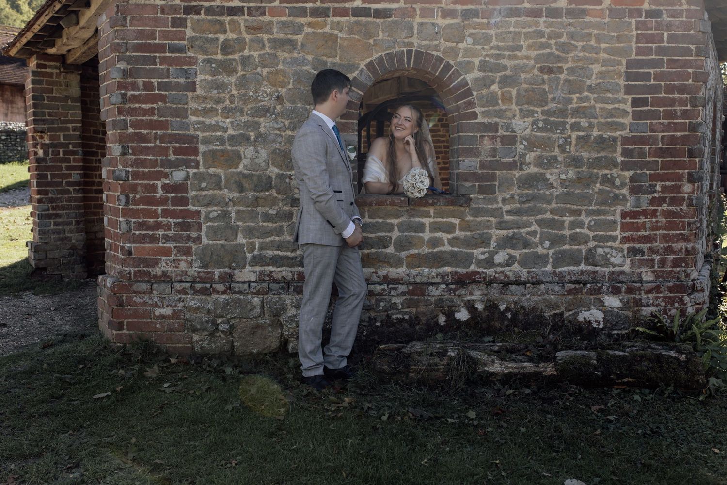 Person in gray suit examines old brick wall texture and architectural details at historic building site.