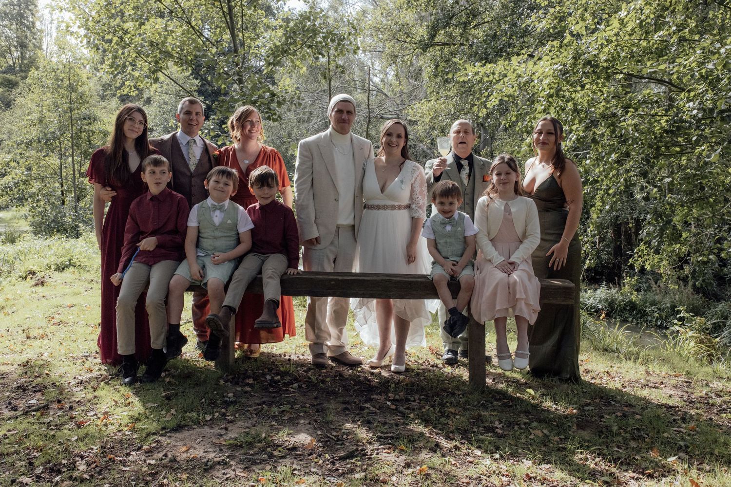 Wedding party poses together in a casual outdoor garden setting surrounded by greenery and natural light.