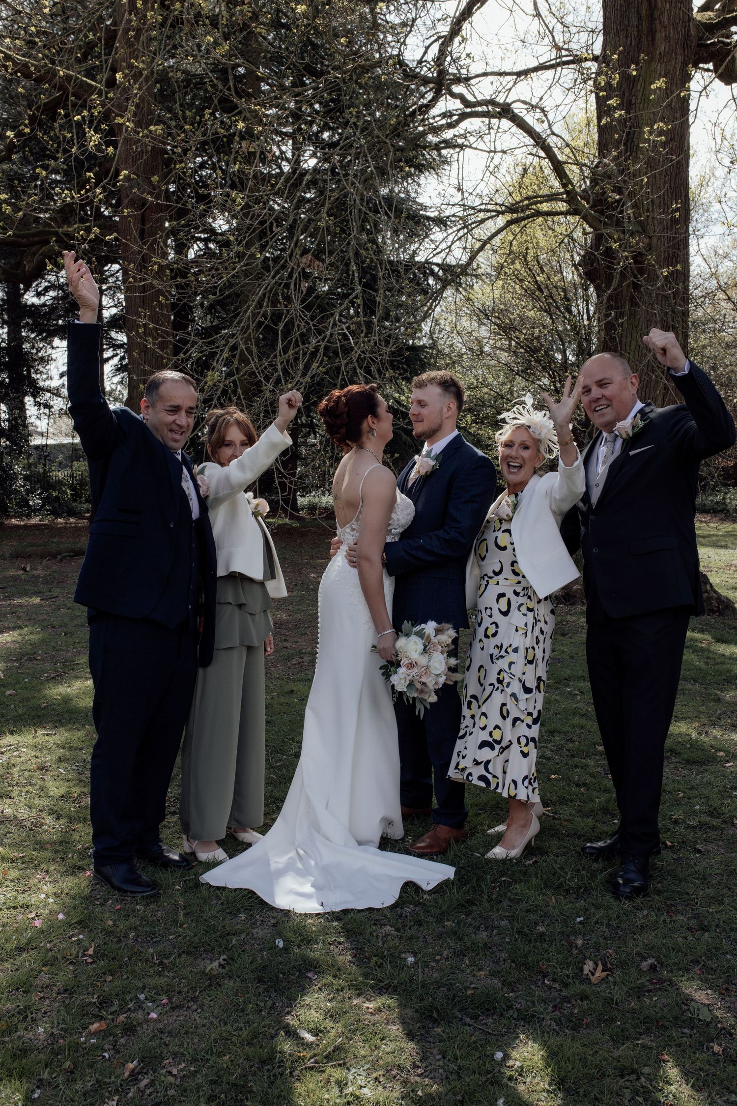 Bride and groom stand facing each other with their family members cheering besides them