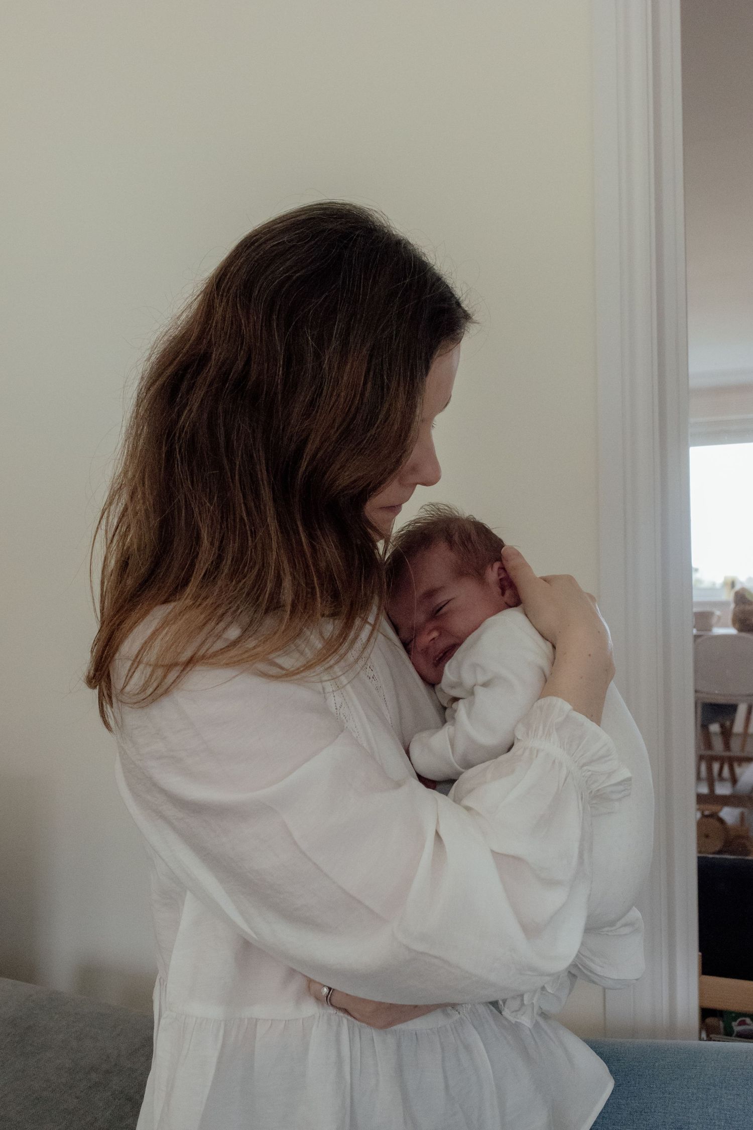 A tender moment between parent and baby as they embrace in a white room.