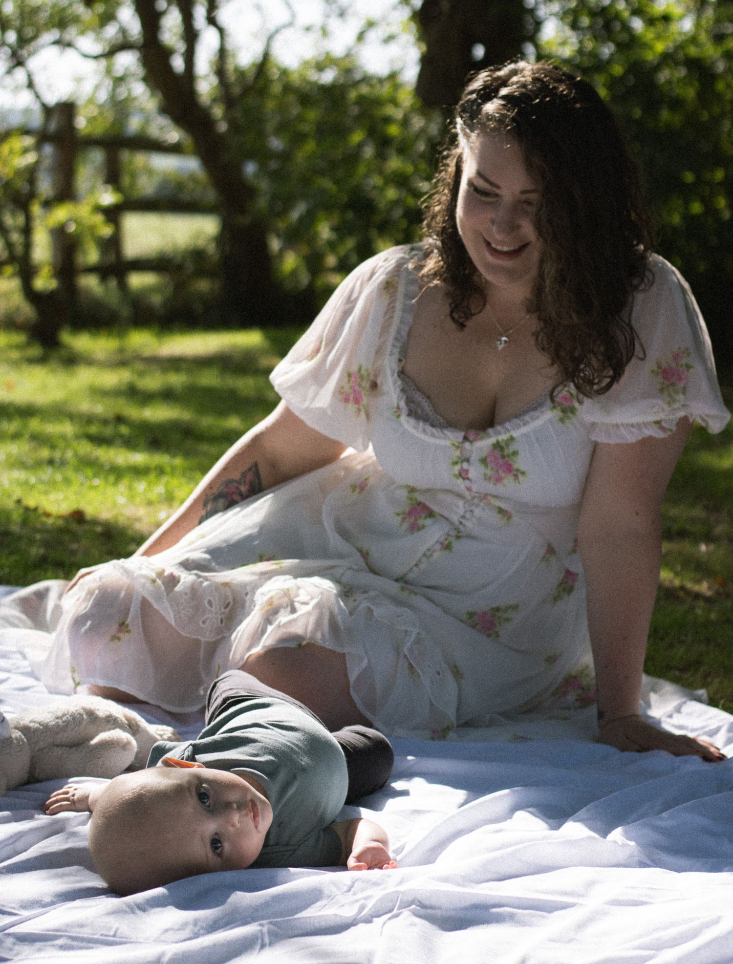 A series of photos showing a tender outdoor photoshoot moment on a white blanket in a sunlit garden setting.